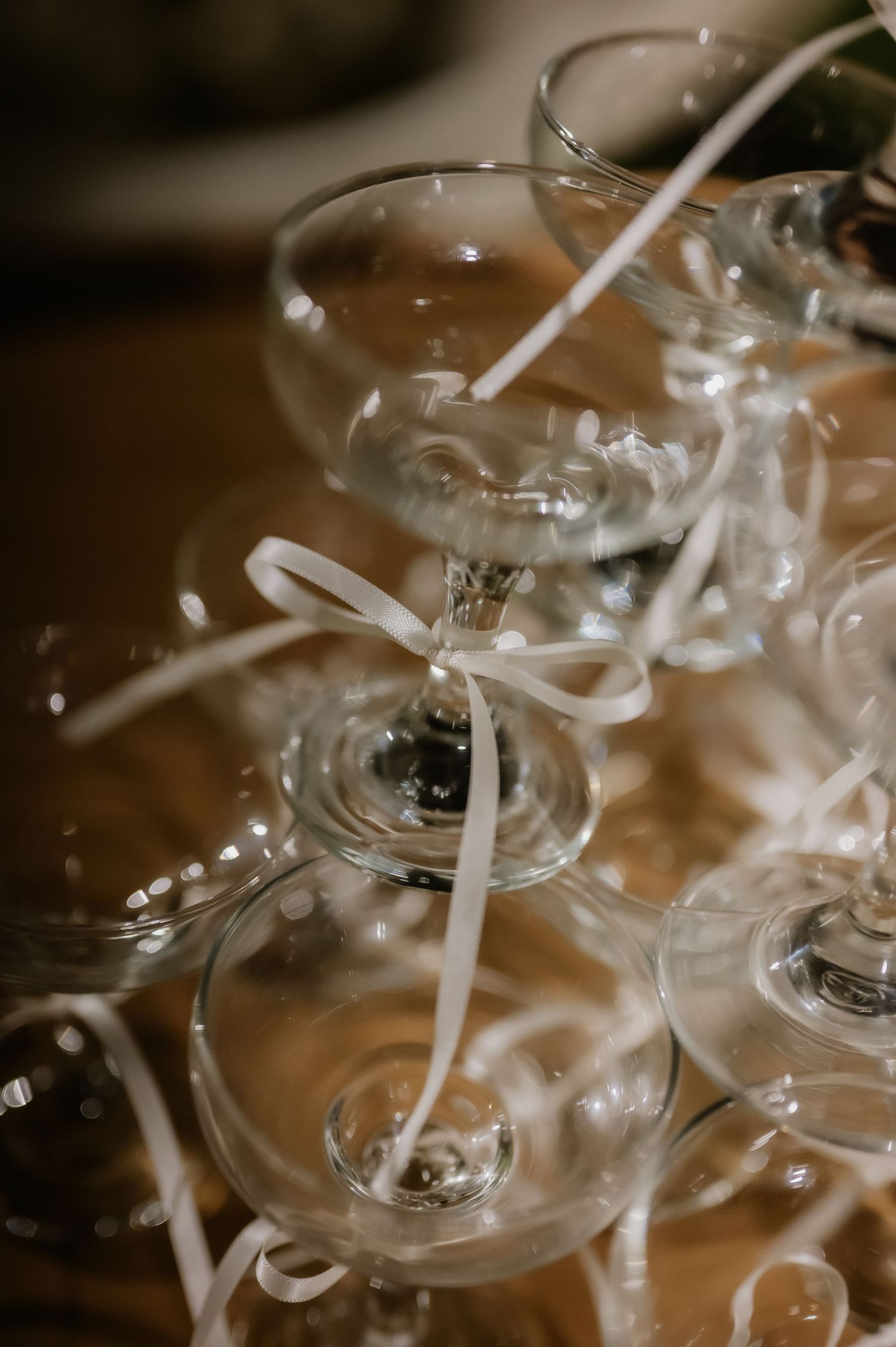 Close-up of stacked coupe champagne glasses tied with white ribbon for elegant wedding tower display.