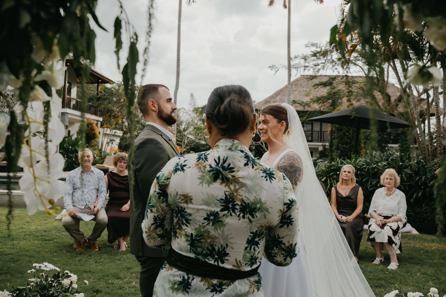 Bride and groom facing officiant during intimate outdoor wedding ceremony with seated guests watching.