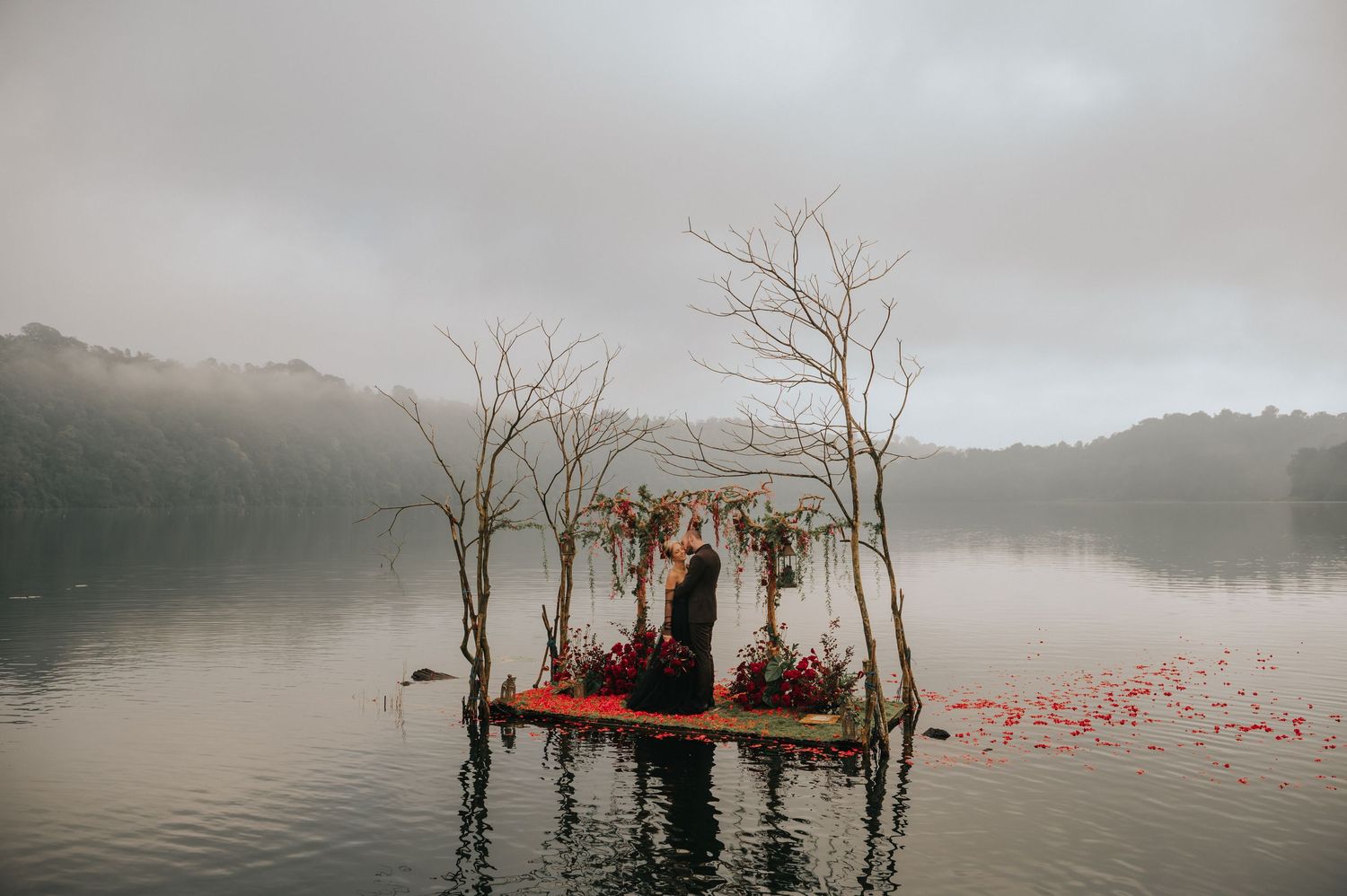 Misty lake landscape with dead trees emerging from foggy waters at sunrise.