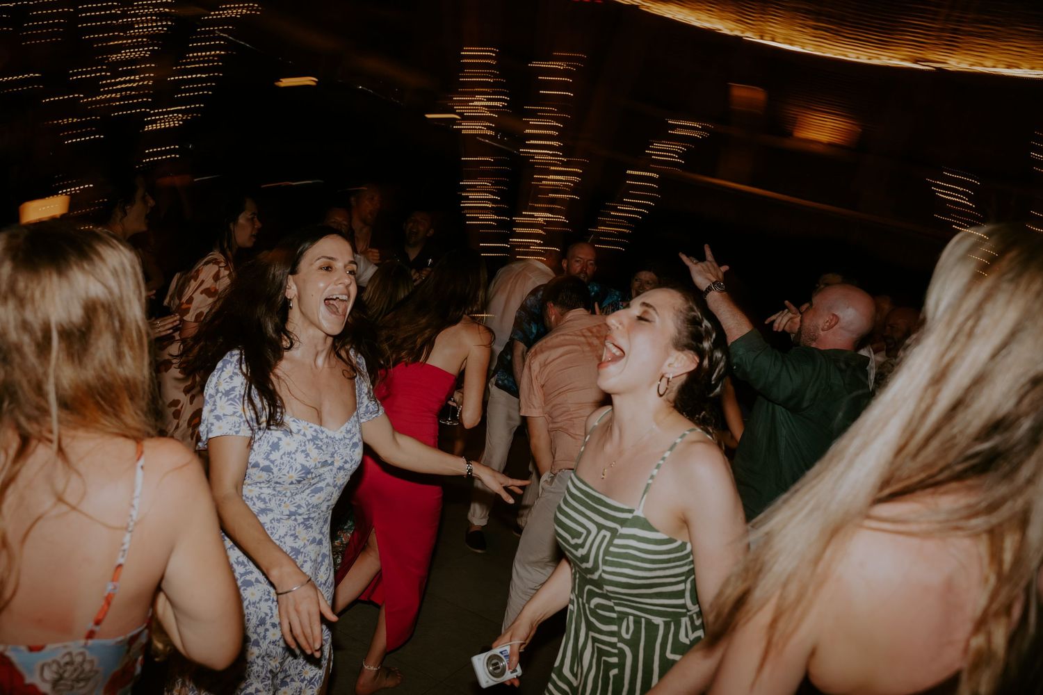 A lively crowd dances together at a nighttime party or celebration event.