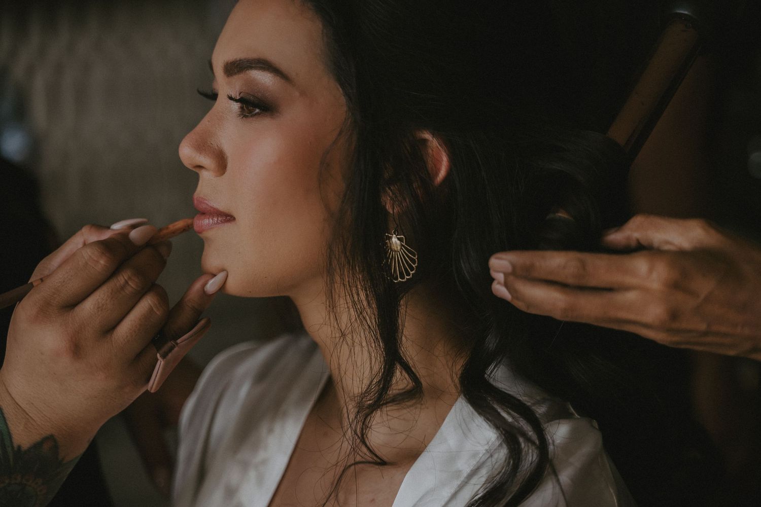 Soft focus beauty preparation scene with makeup brushes in dark moody lighting.