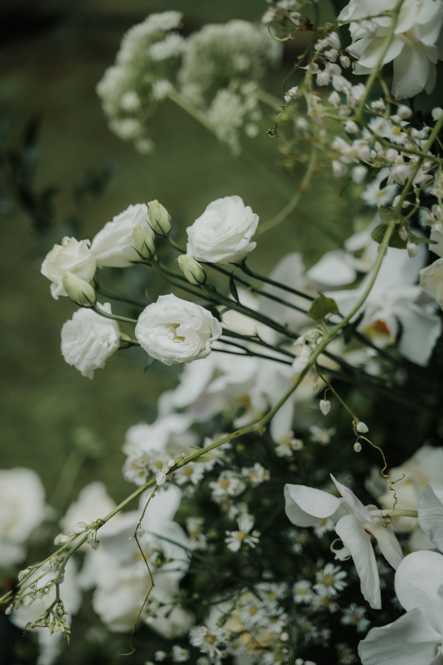Close-up of delicate white roses and wildflowers in a lush bridal floral arrangement.