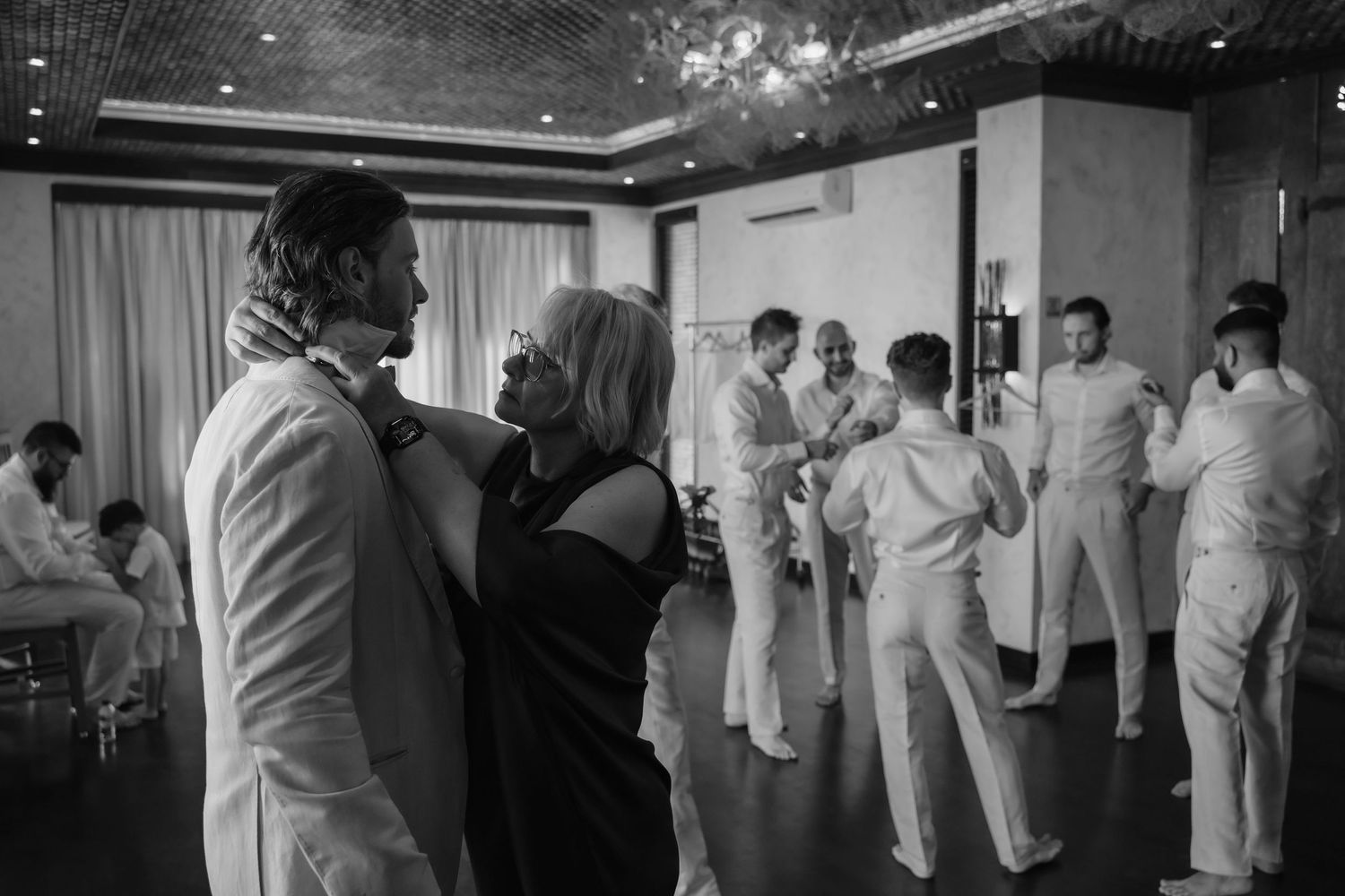 Black and white photo of elegantly dressed guests socializing and dancing at an upscale indoor event or wedding reception.