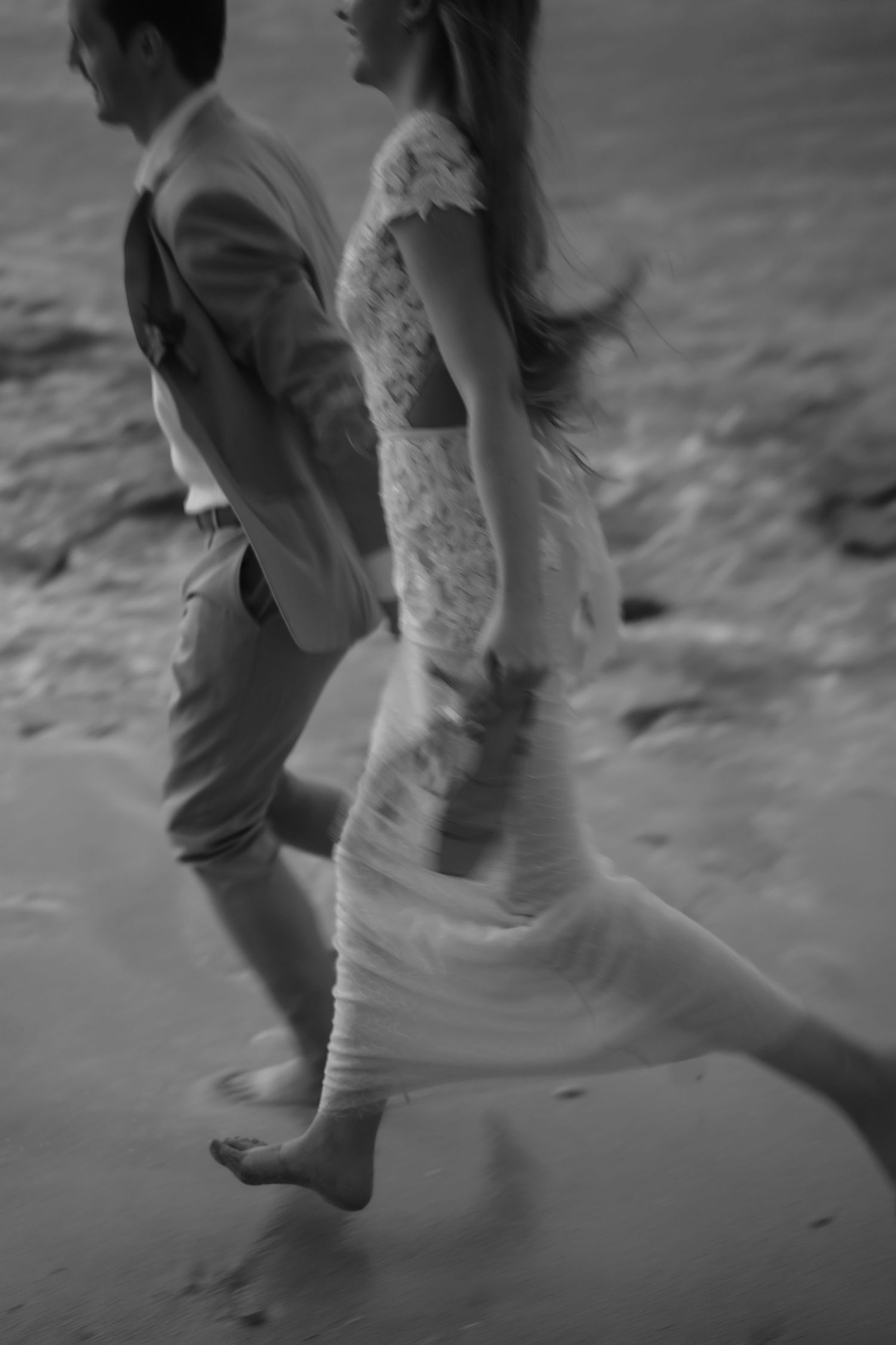 Close-up of feet walking on sandy beach in black and white photography.