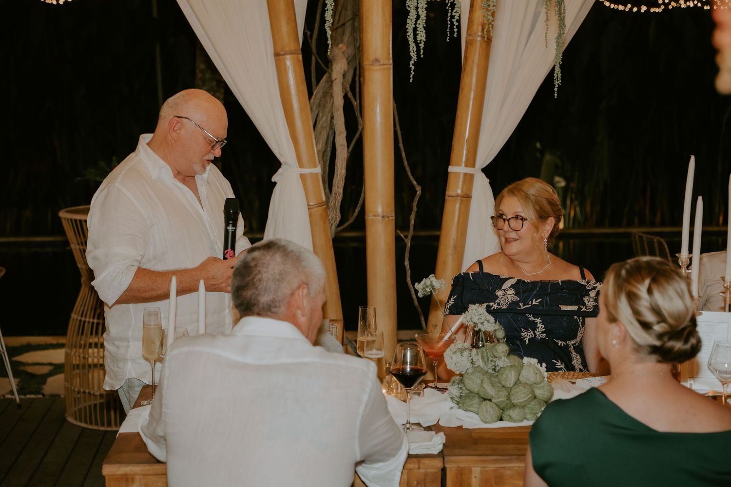 Father of the bride giving a heartfelt speech at an intimate candlelit reception.