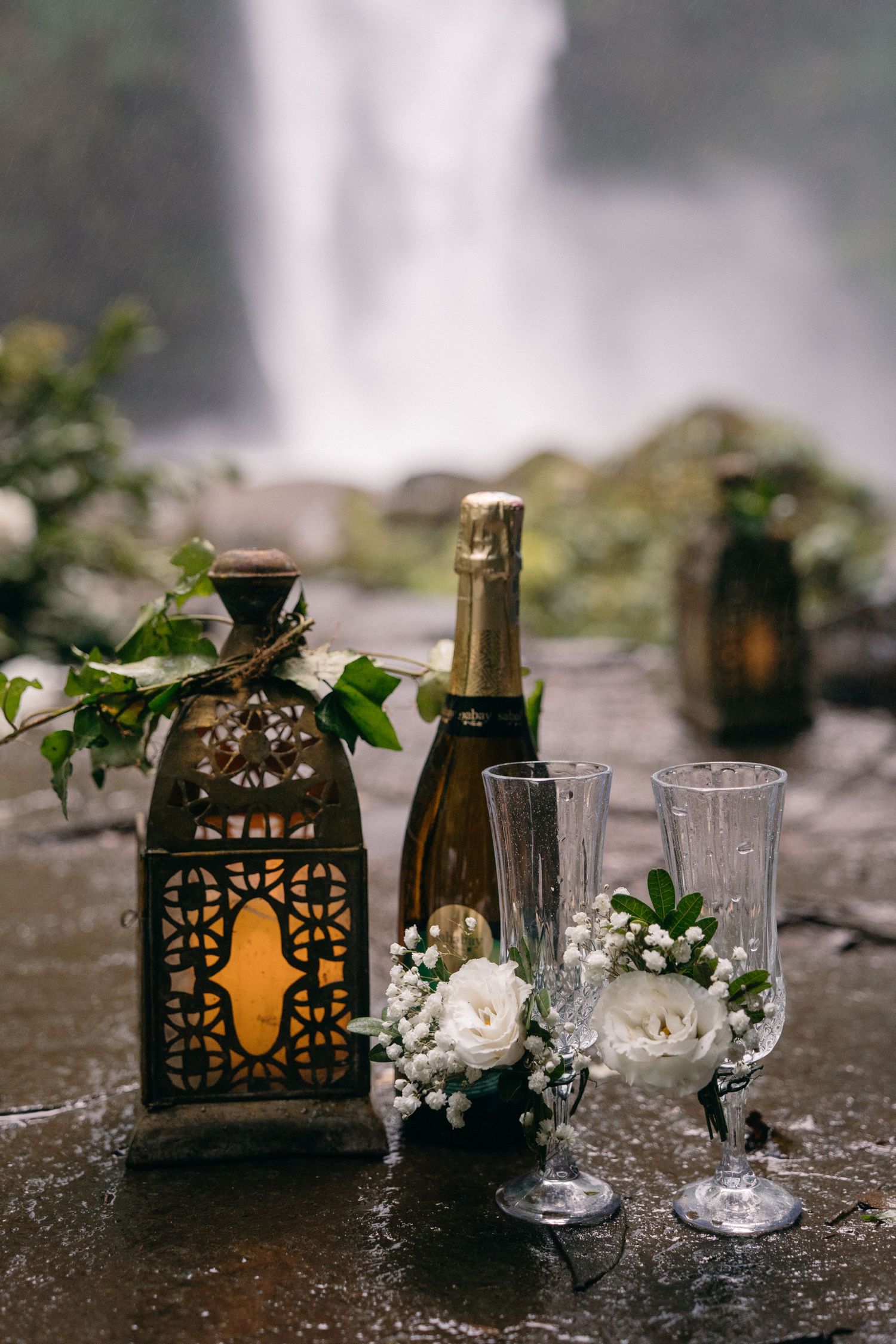 Rustic wedding decor featuring ornate black lanterns and crystal champagne glasses with delicate baby's breath flowers.