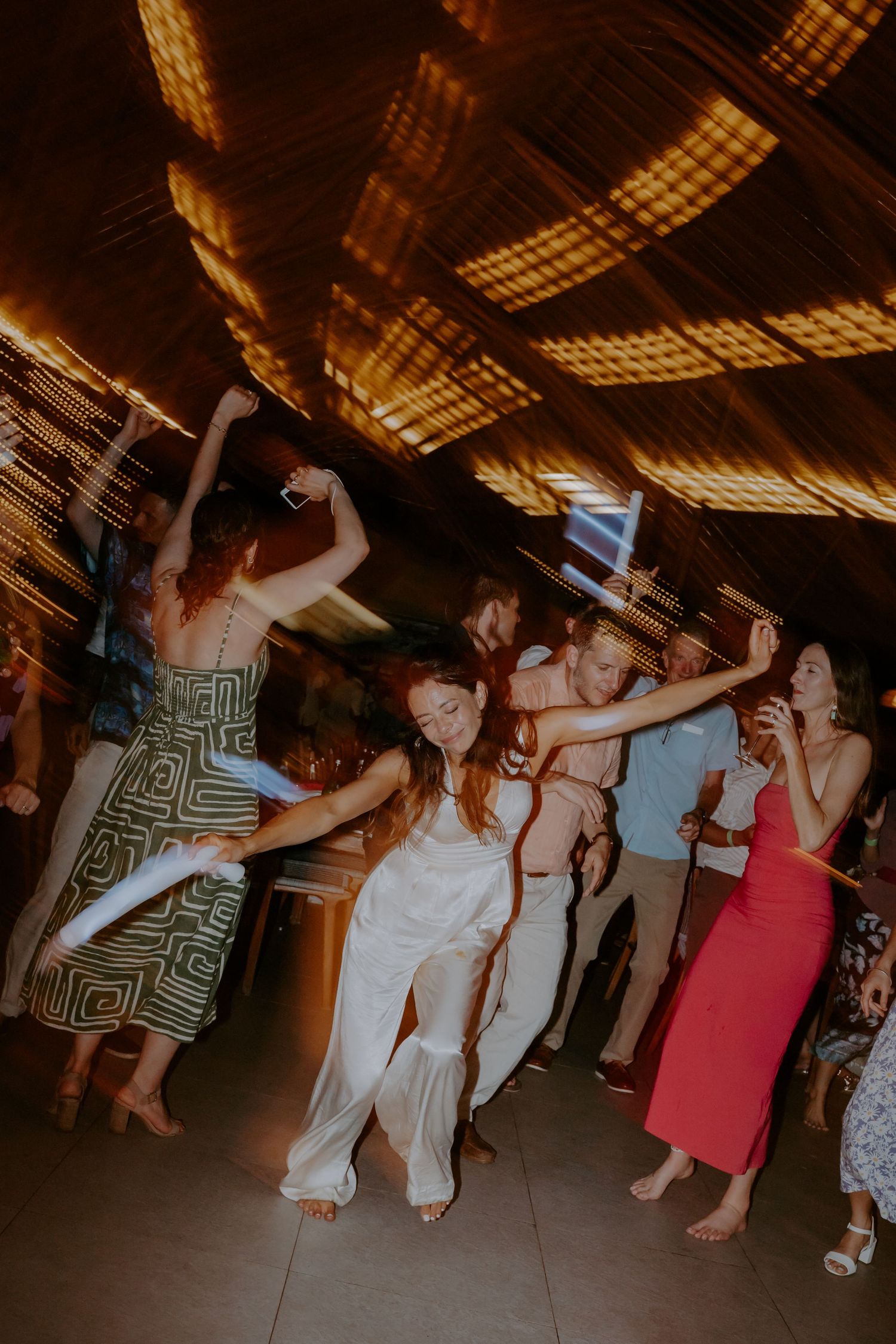 Party guests dancing and celebrating on a dimly lit dance floor at an indoor event venue.