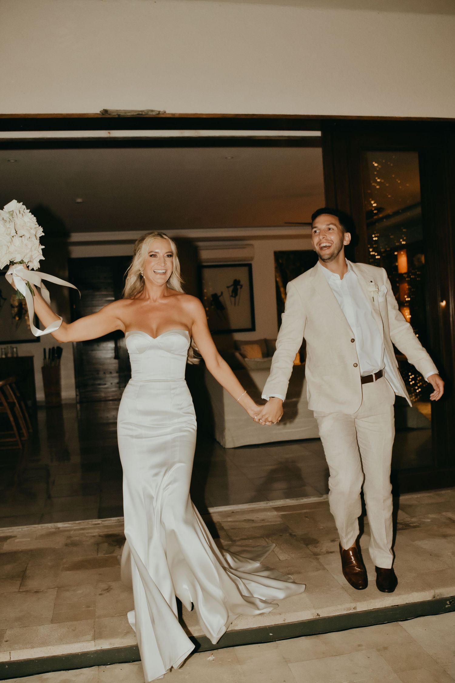Smiling bride and groom hold hands as they make their grand entrance at their wedding reception.