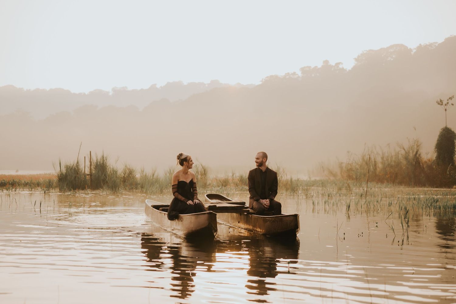 Serene lake scene with canoes gliding through morning mist and forest reflections.