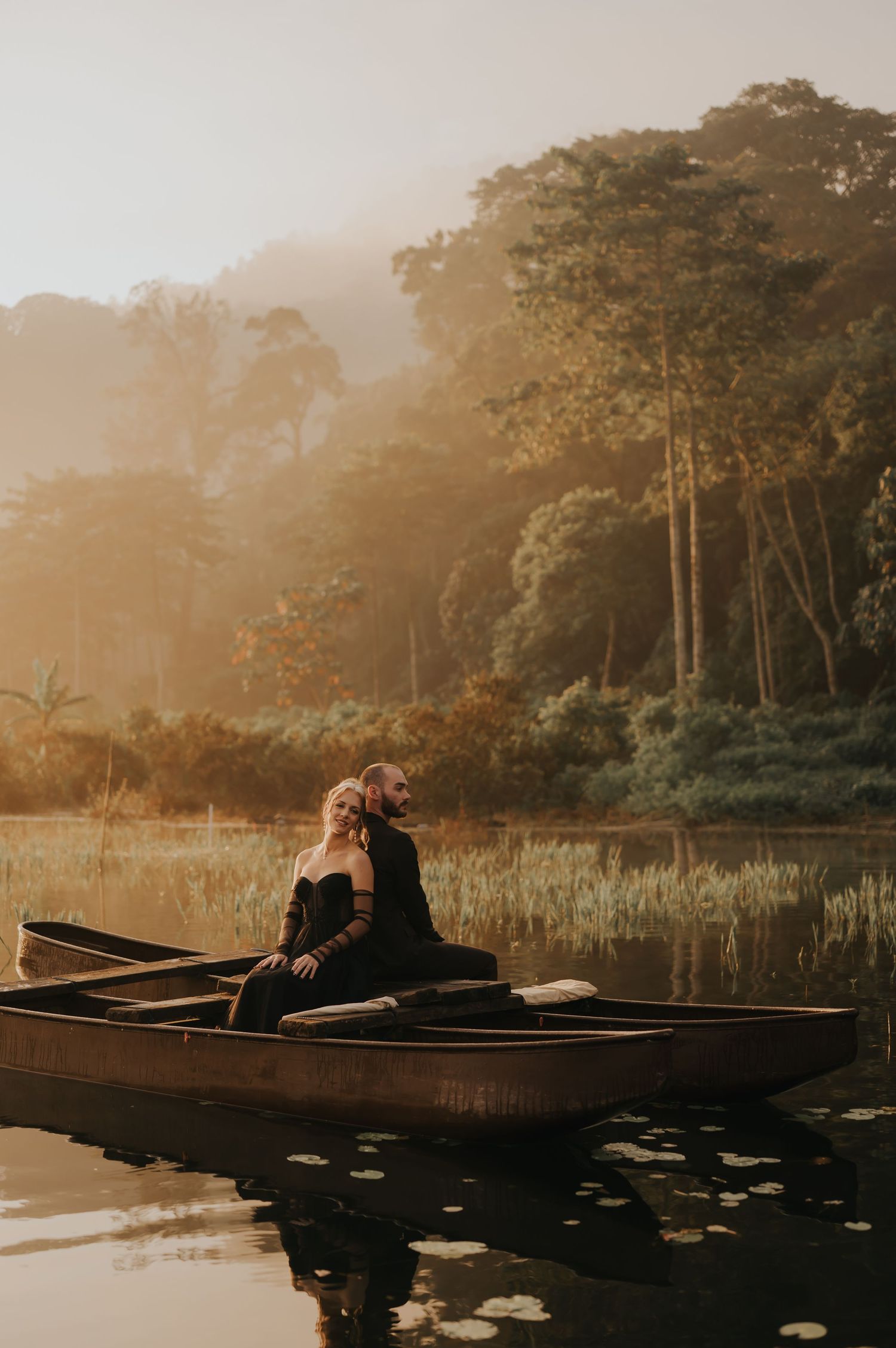 Romantic canoe engagement photos on a serene lake surrounded by trees at sunset.