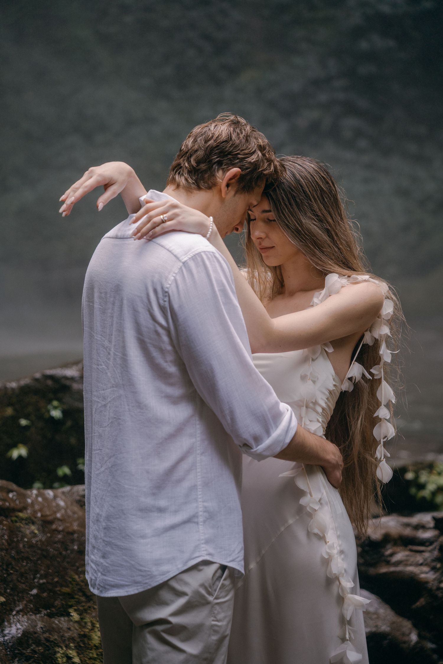 A romantic couple embraces in a series of intimate poses against a moody dark background.