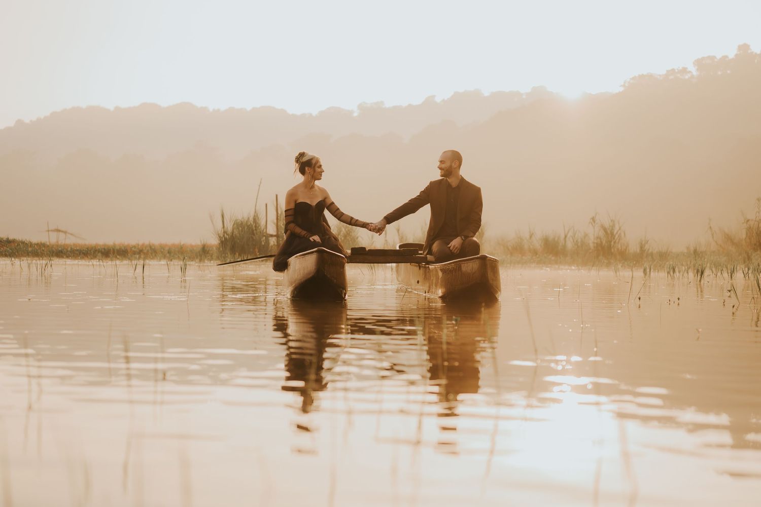 Romantic silhouettes of a couple sitting by a serene lake during golden hour.