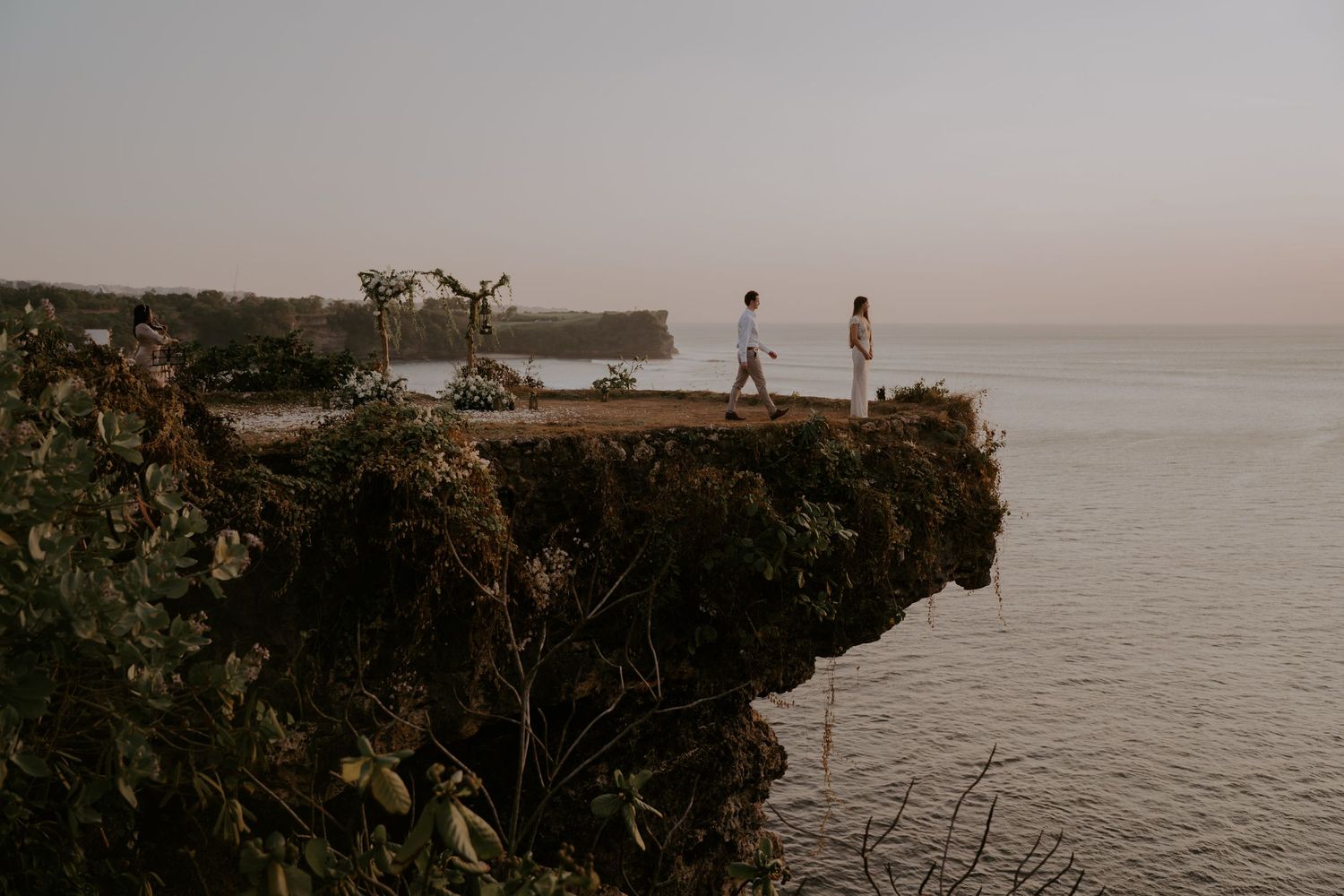 Dramatic cliffside ocean view with people silhouetted against the horizon.
