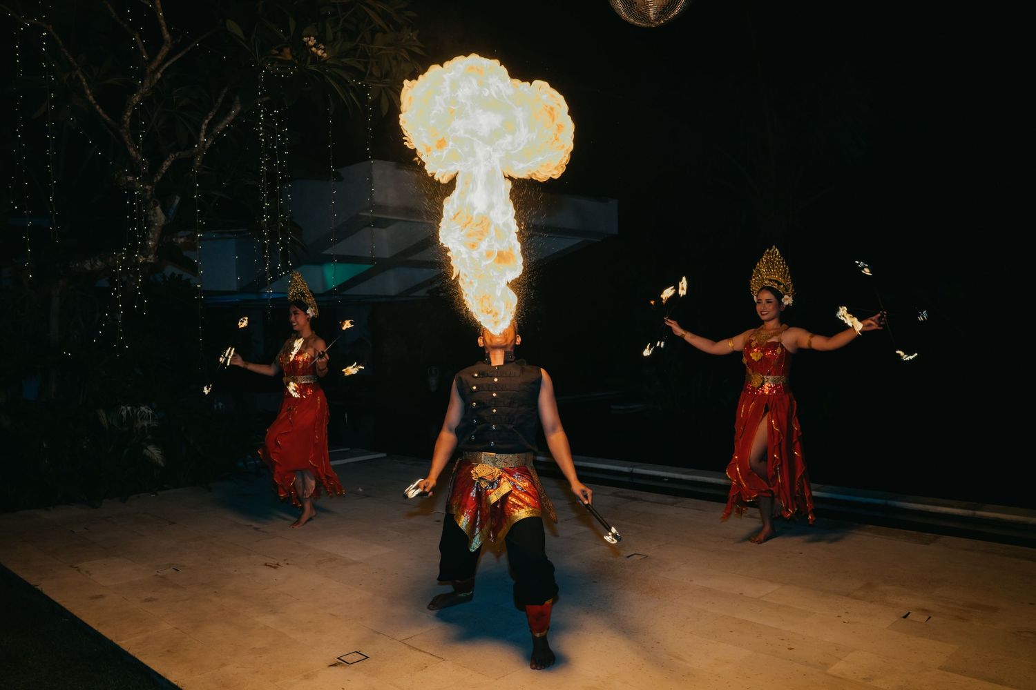 Traditional Balinese fire dancers perform dramatic fire-breathing show at outdoor wedding entertainment.