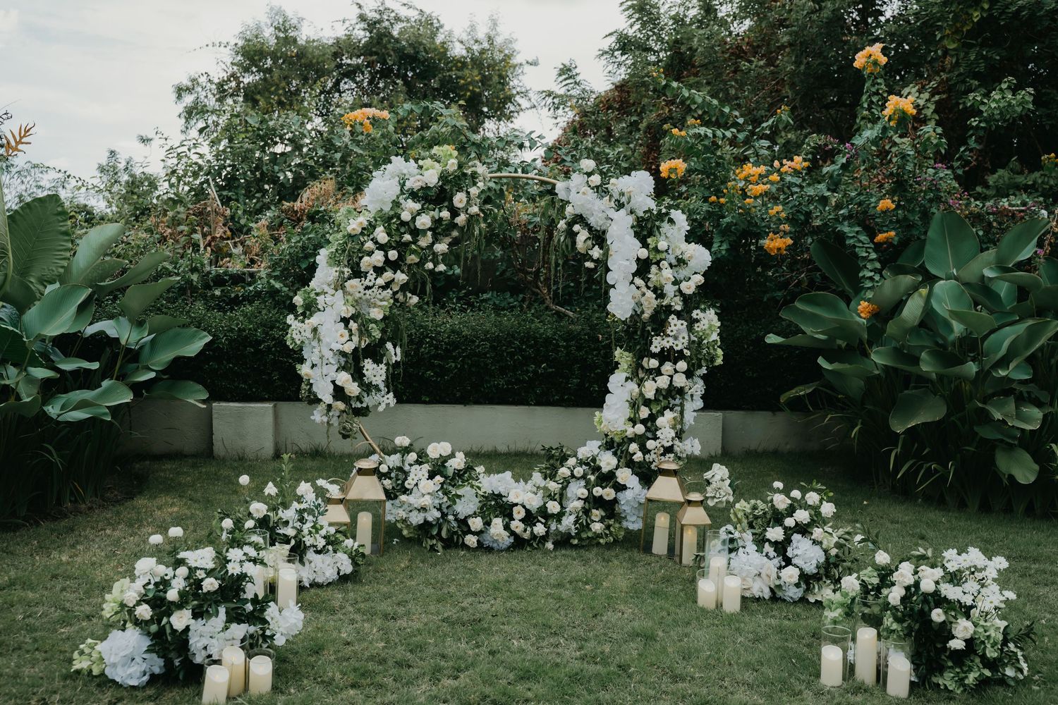 Elegant outdoor wedding arch adorned with white flowers and candles.