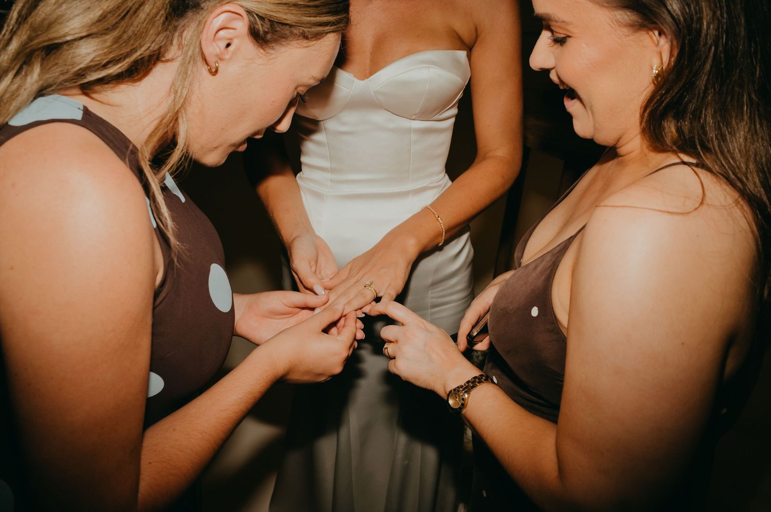 Two bridesmaids admiring the brides wedding ring at a nighttime reception celebration.