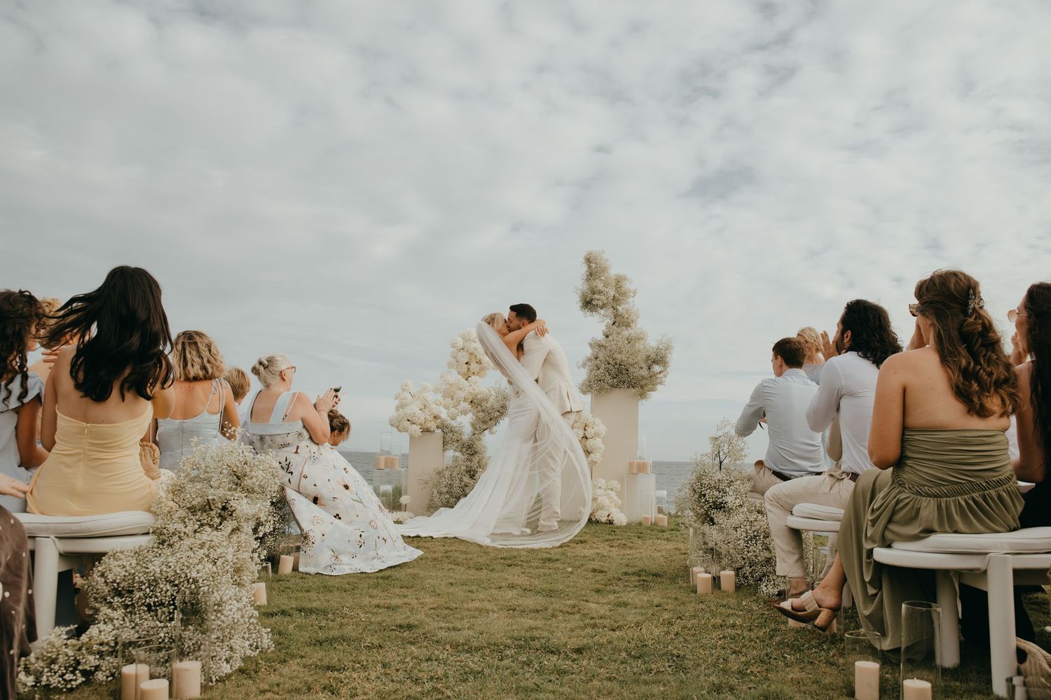 Bride and groom share a first kiss at the altar during an outdoor clifftop wedding ceremony.