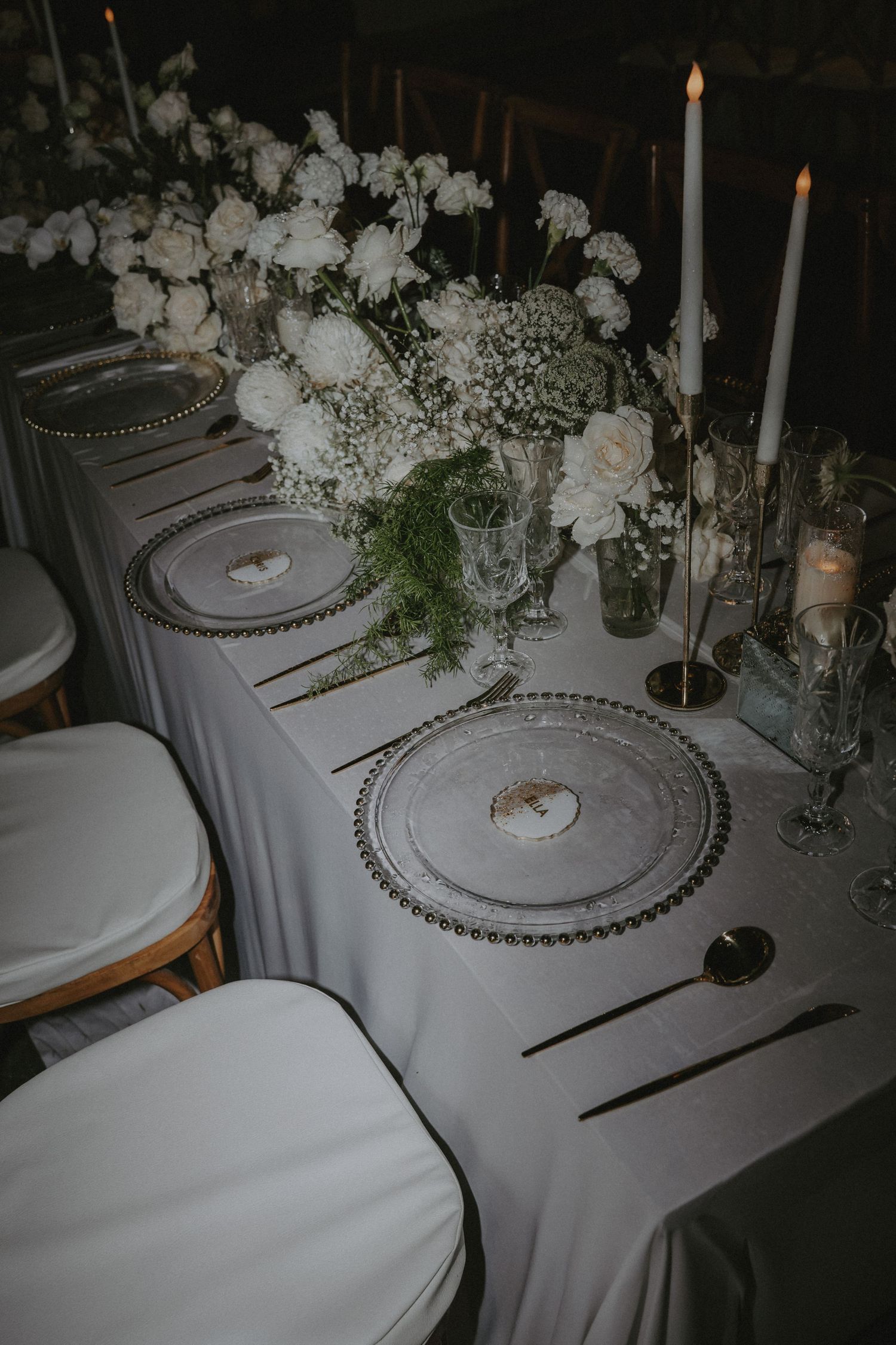 Elegant wedding table settings with white linens, beaded charger plates, and candlesticks create a romantic atmosphere.
