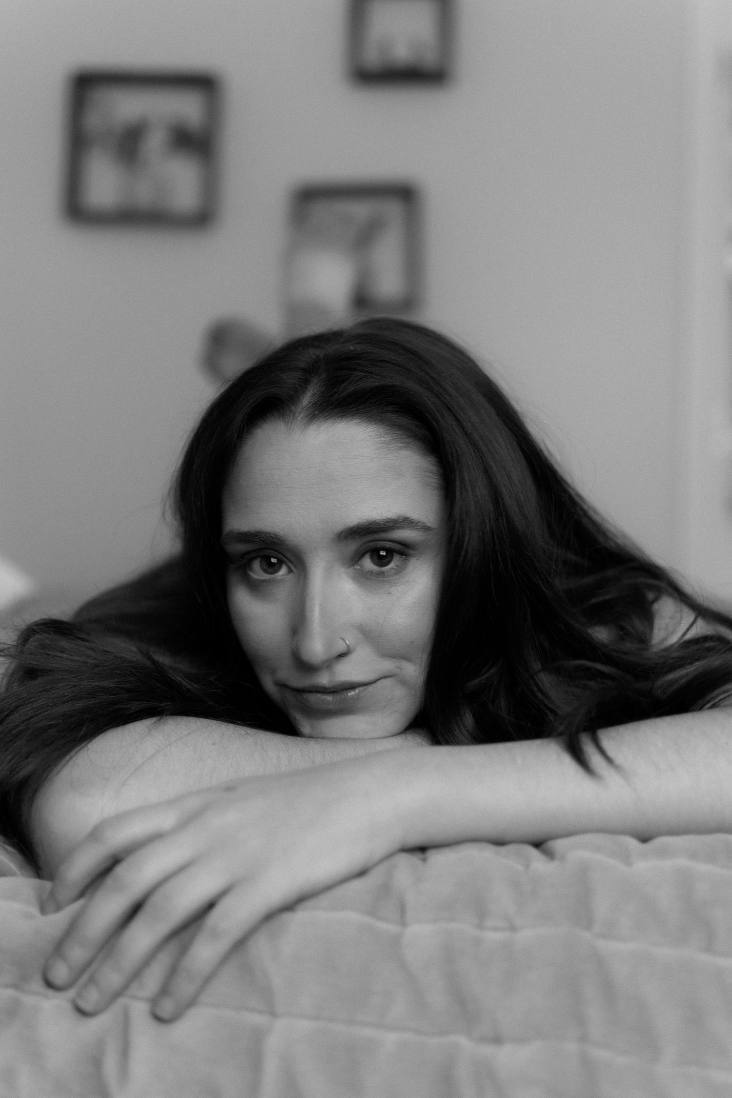 A woman smiles softly on a bed.