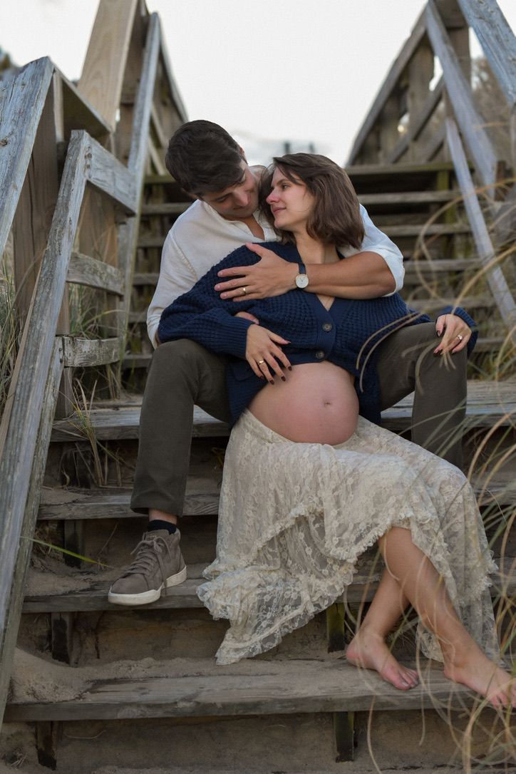 A pregnant woman is held by a man on a staircase.