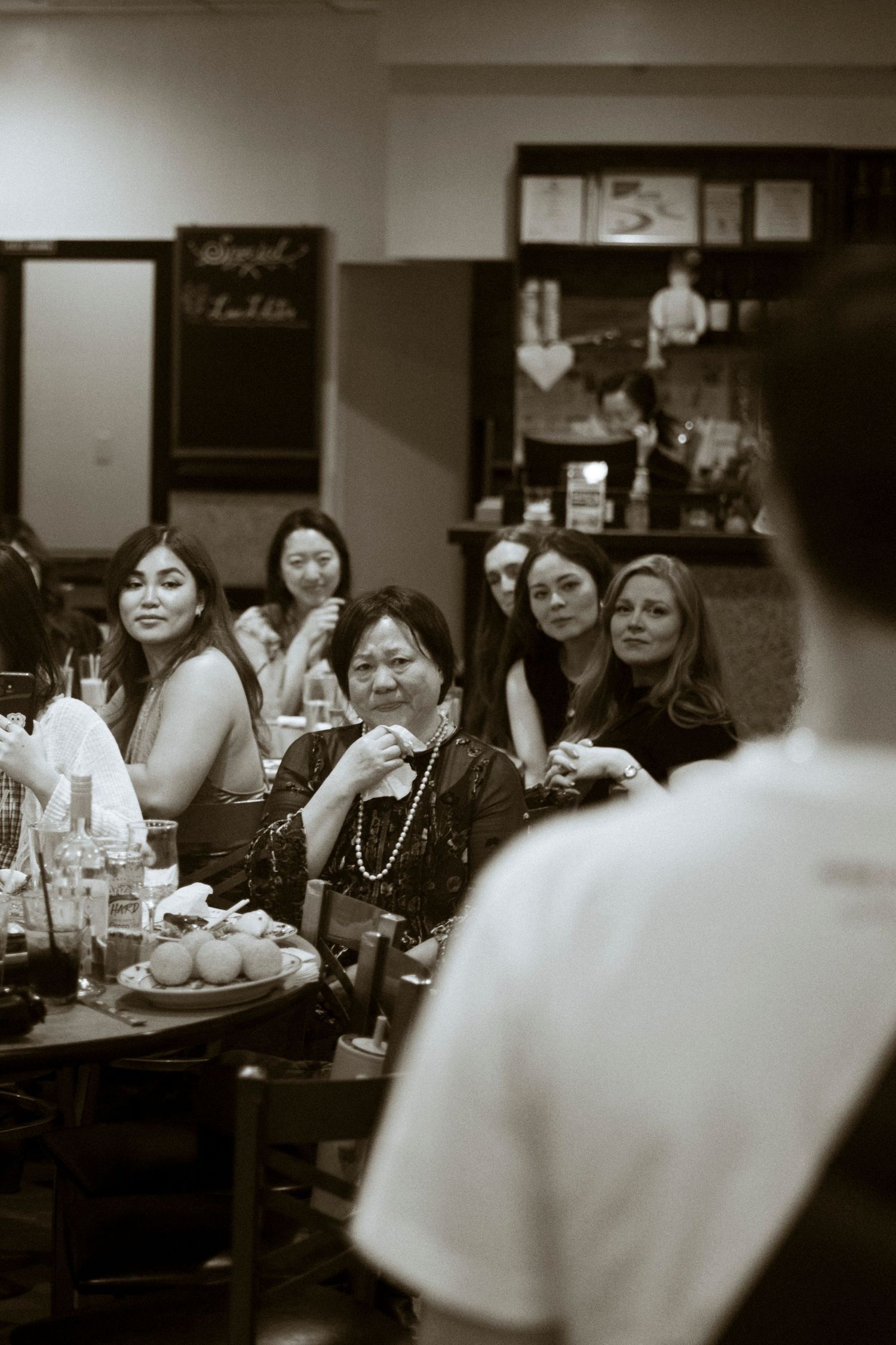 A woman looks at an out of focus speaker.