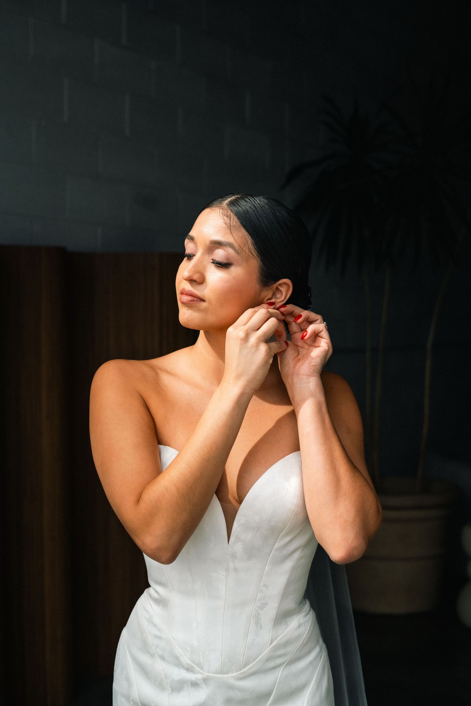 A bride placing an earring in her right ear.