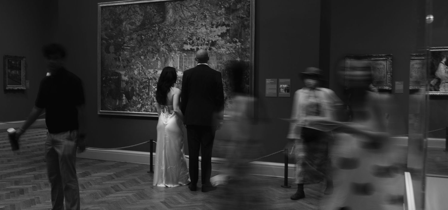 Museum visitors view artwork on display in a black and white photograph showing blurred motion and silhouettes at DSM art institute