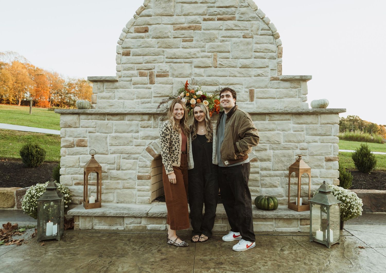 Family poses together against stone fireplace backdrop with lantern decorations.