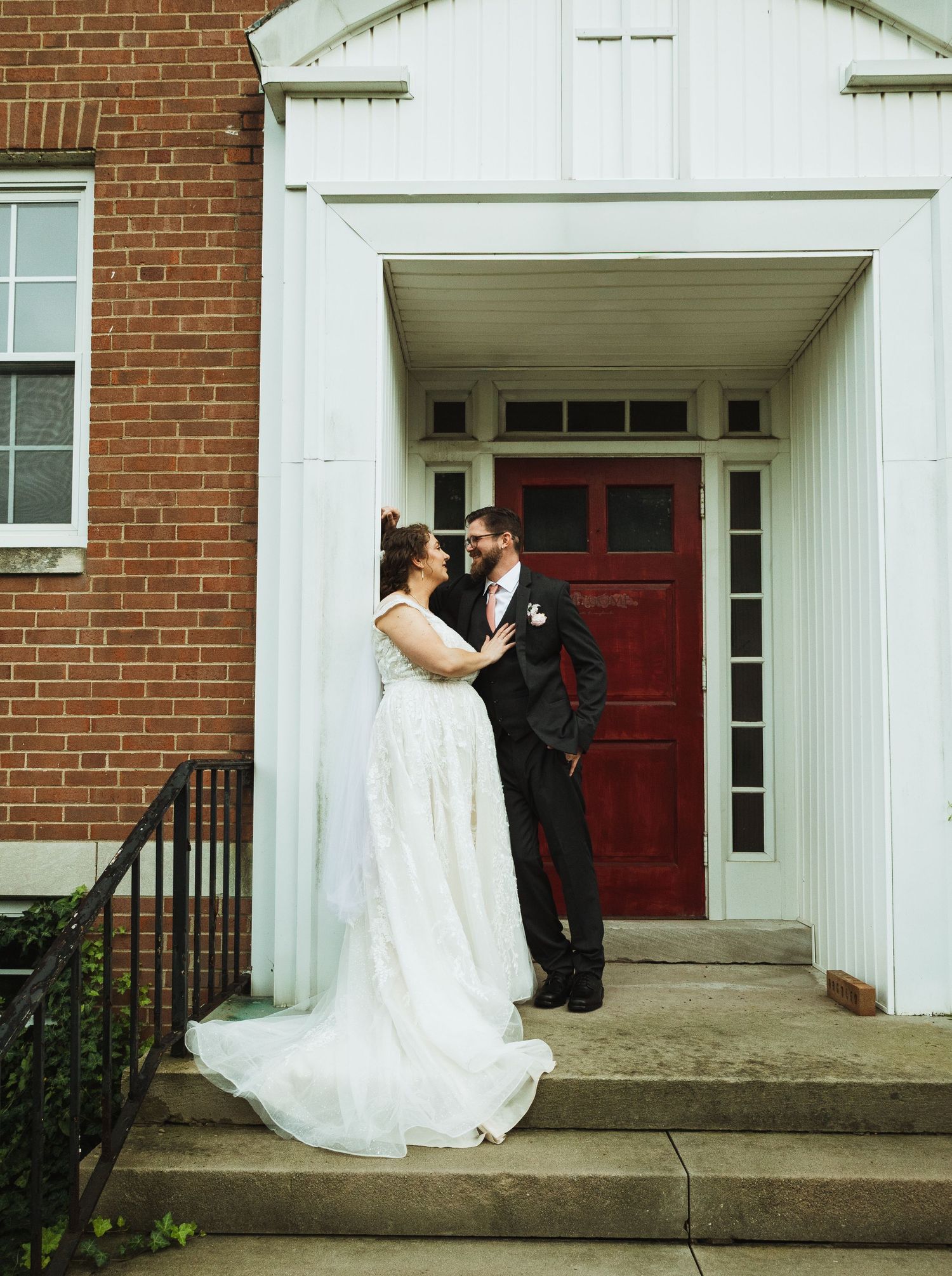 A romantic first look sequence outside a brick church with white columns and red doors.
