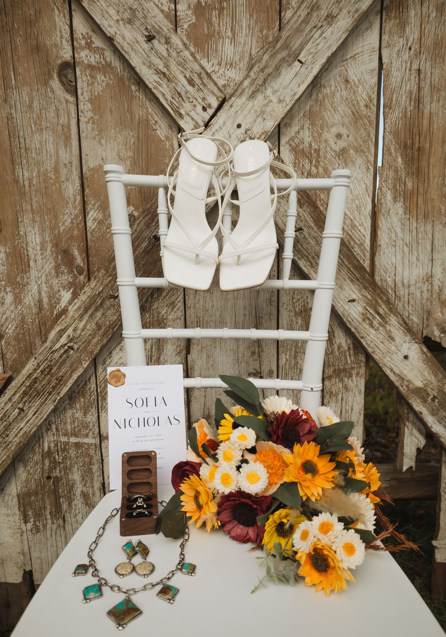 Wedding reception decor featuring white chairs and sunflower arrangements against rustic wood.