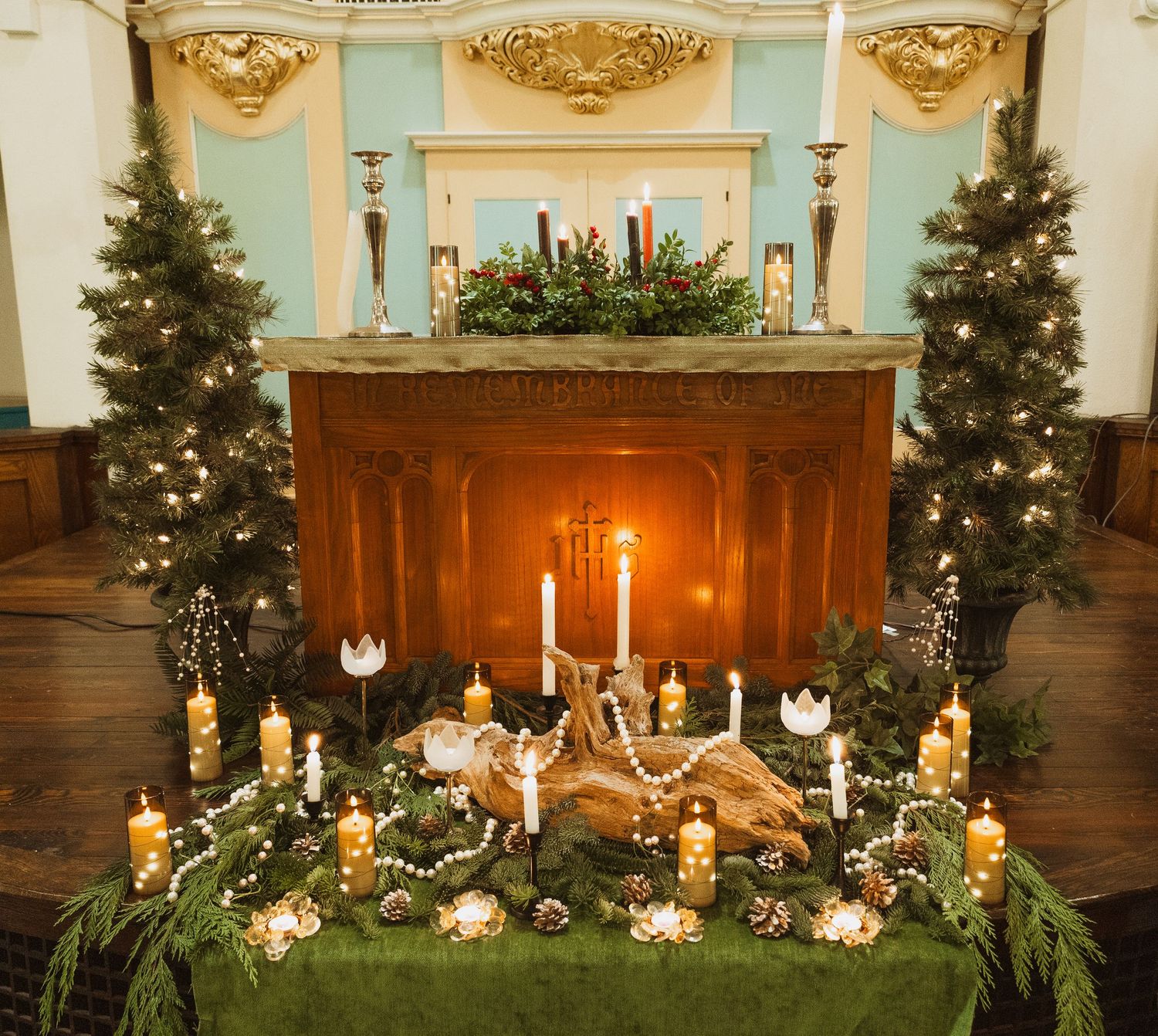 Ornate church altar decorated with candles, greenery, and Christmas trees for winter wedding.