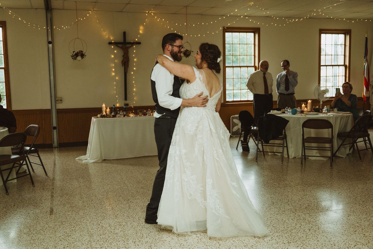 Wide angle view of a wedding reception venue with string lights and couples dancing on the floor.