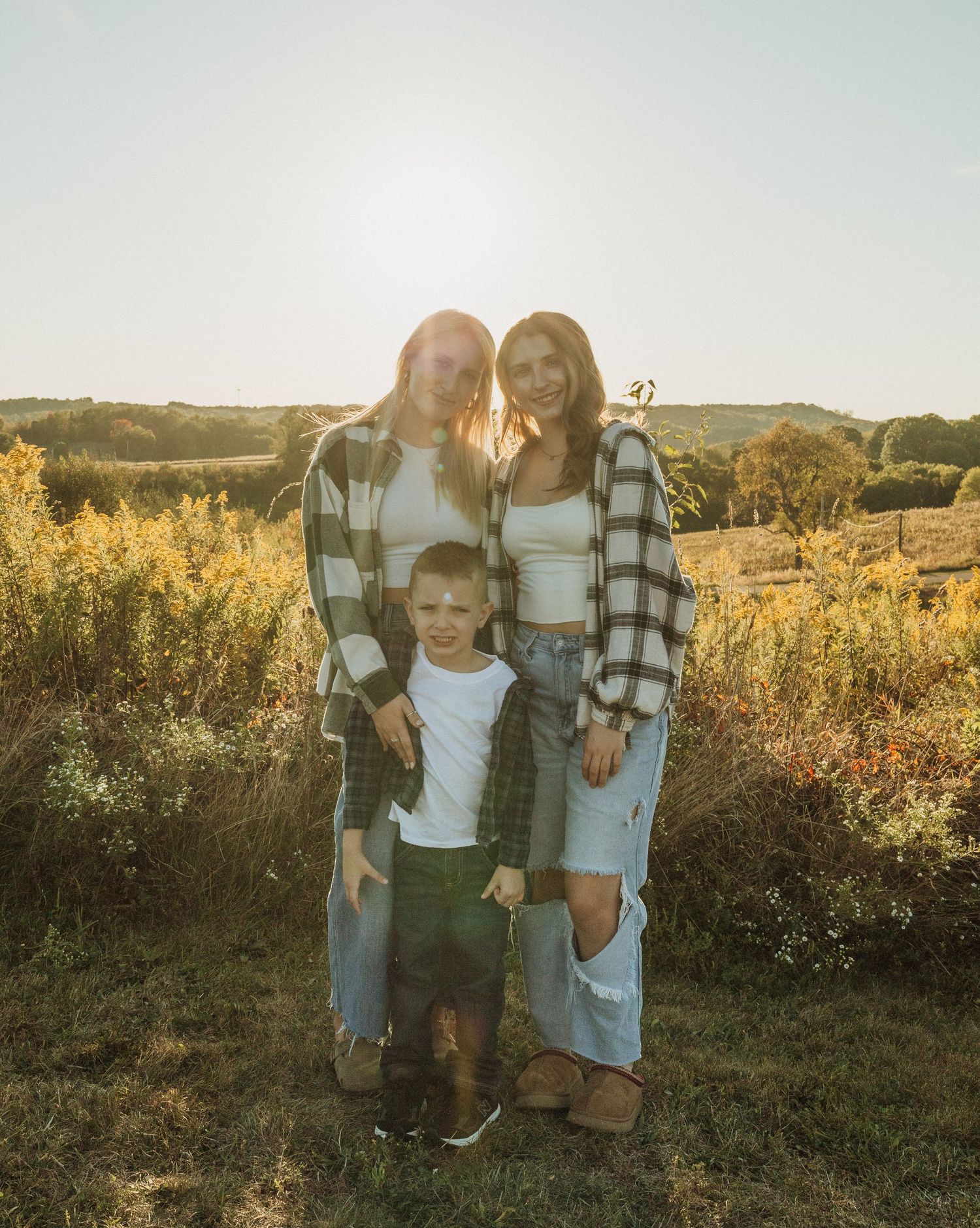 Family of five posing together outdoors during golden hour in autumn field.