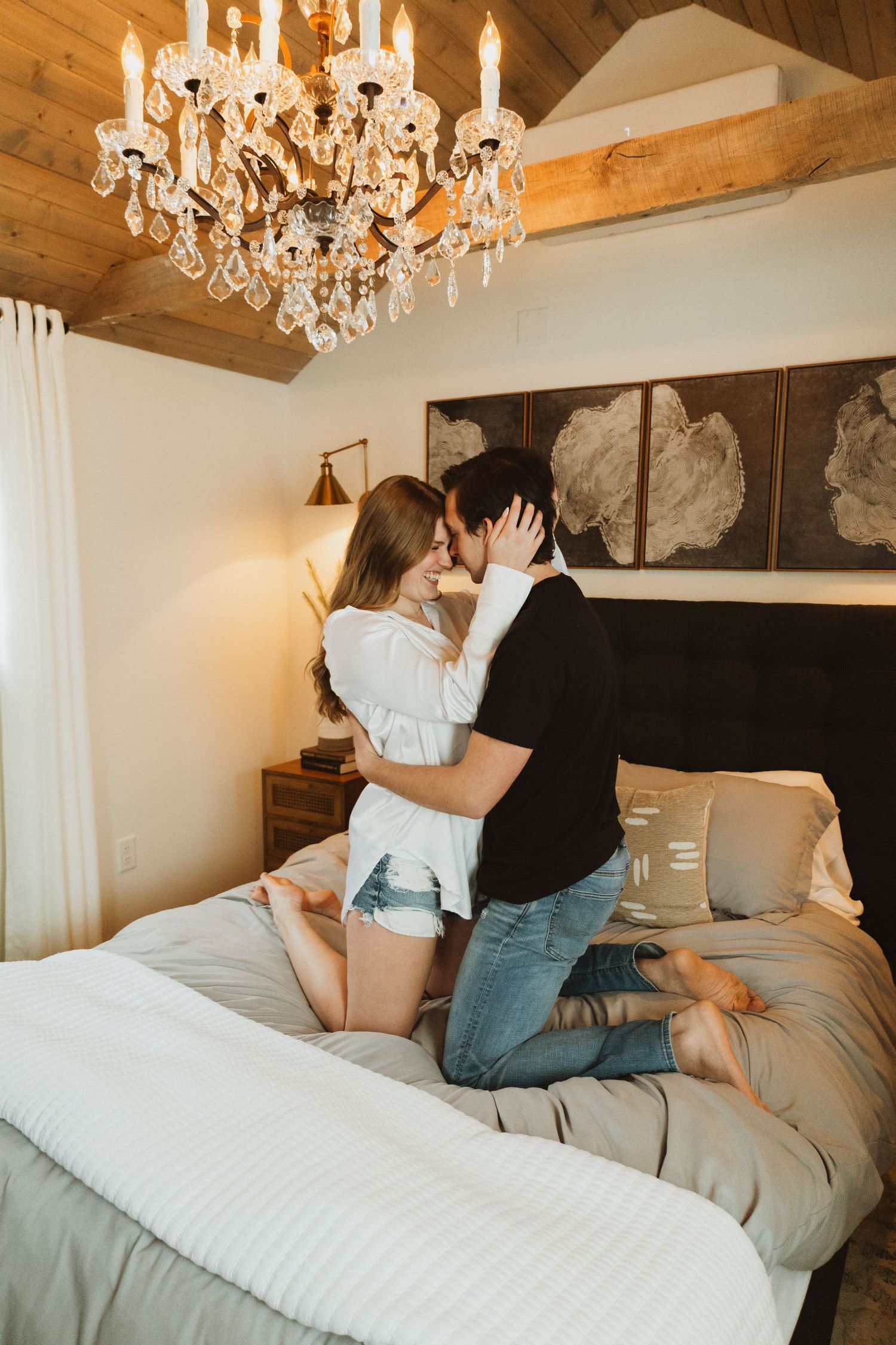 Interior bedroom scene with crystal chandelier and wooden beam ceiling.