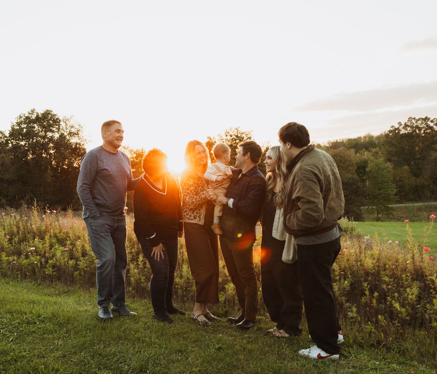 Group photo at sunset with golden light streaming through trees in background.
