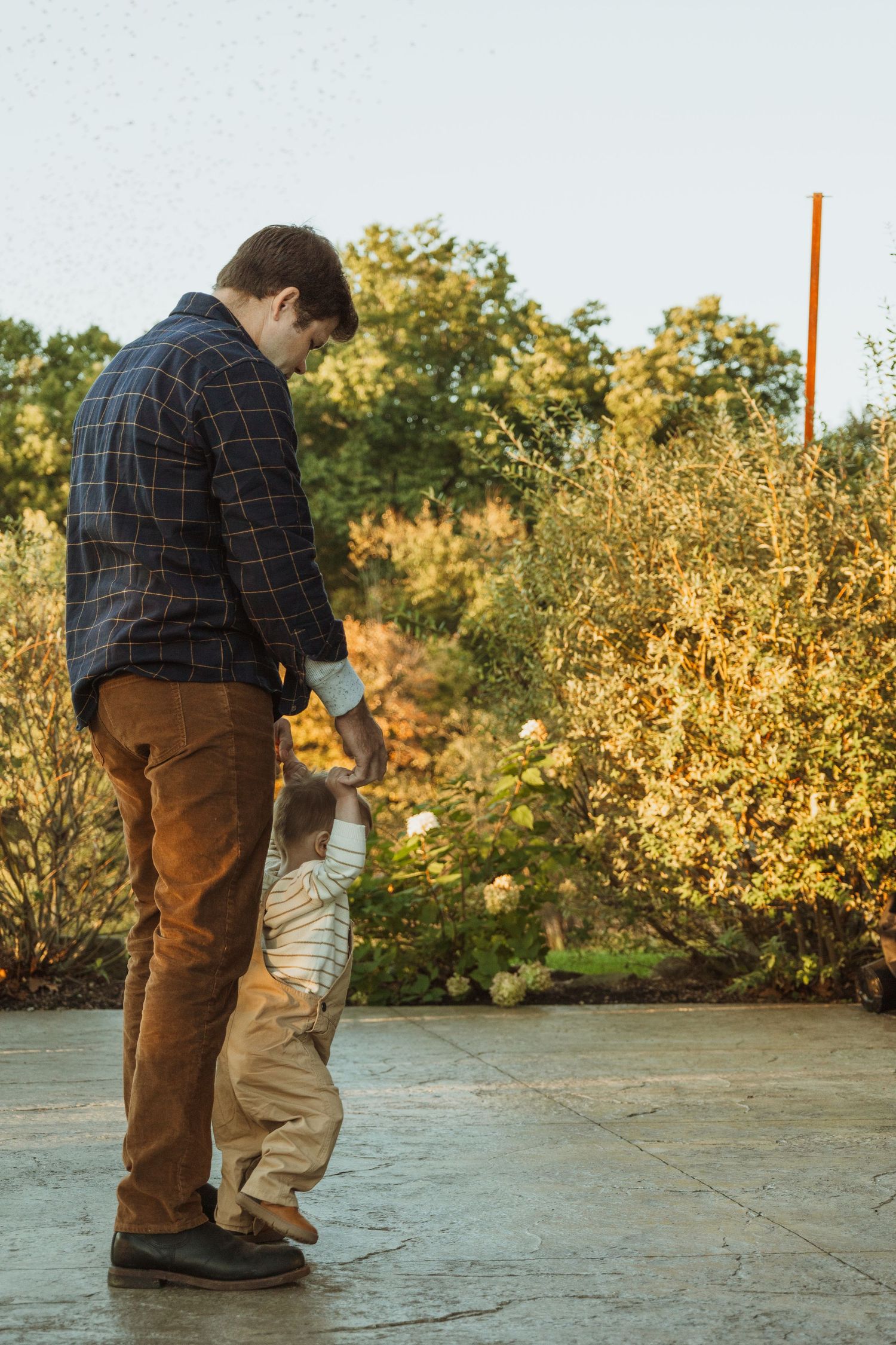 Parent and child share a tender moment on an outdoor patio during golden hour sunset.