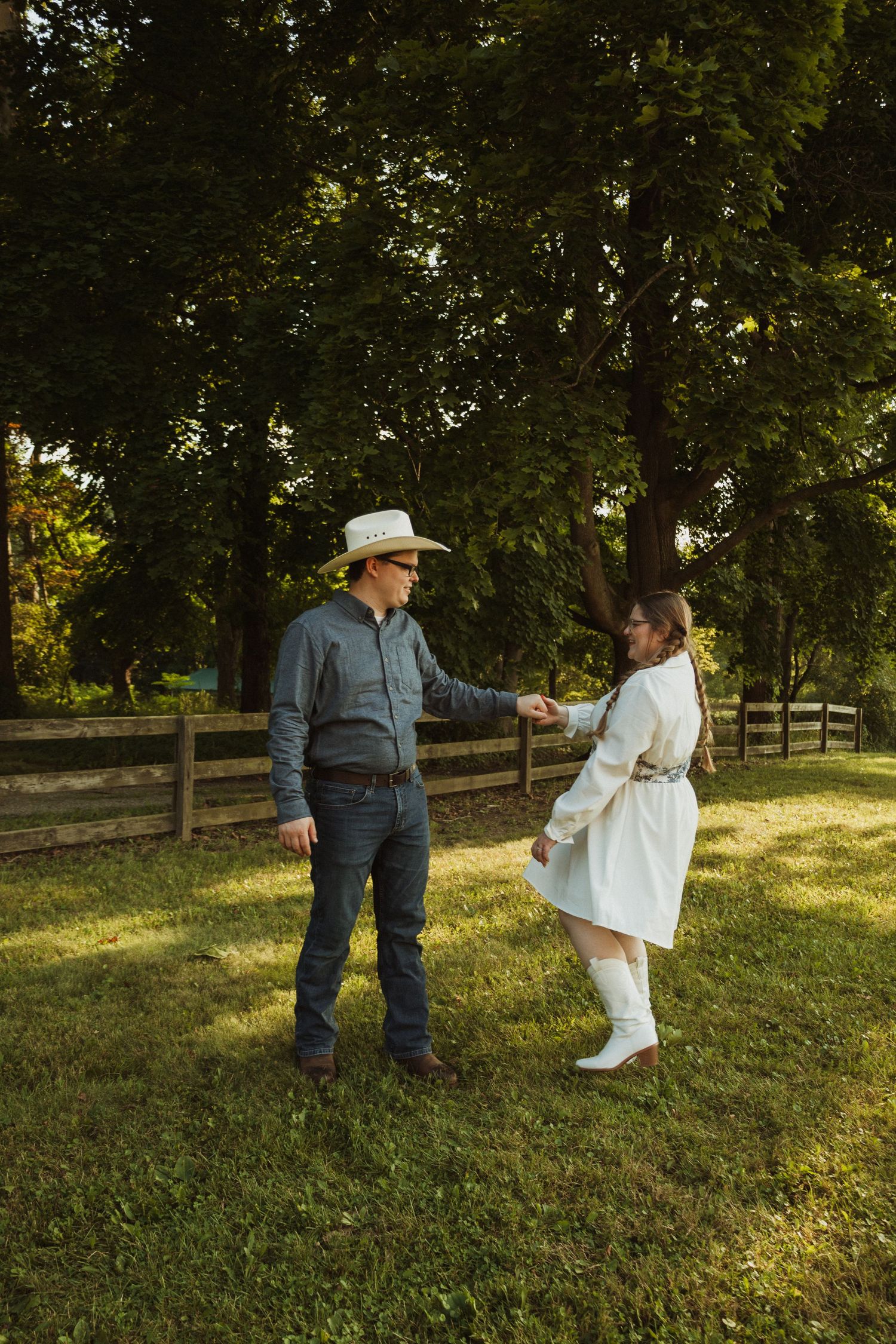 Two people share a heartwarming moment on a sunlit lawn with wooden fencing in the background.
