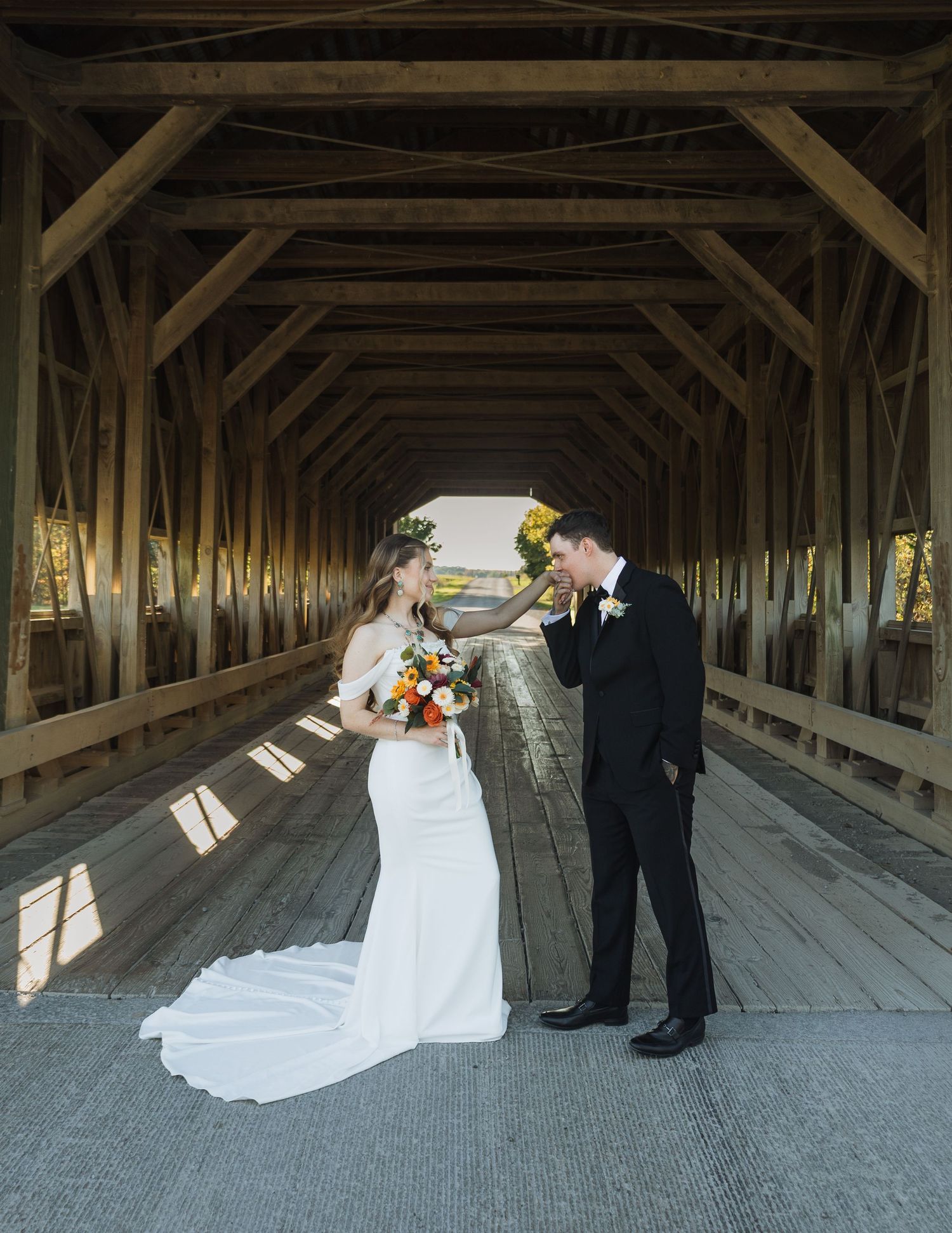 Wedding couple poses inside a rustic covered wooden bridge in a series of romantic shots.
