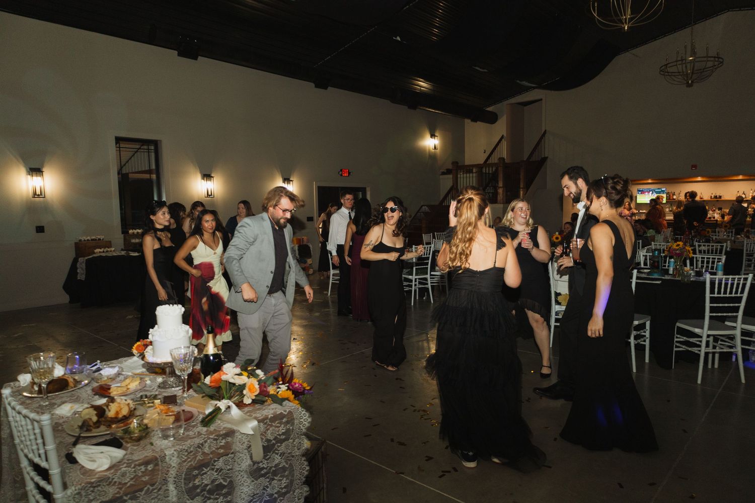Dark reception hall with ambient lighting and dining tables set up for an evening wedding celebration.