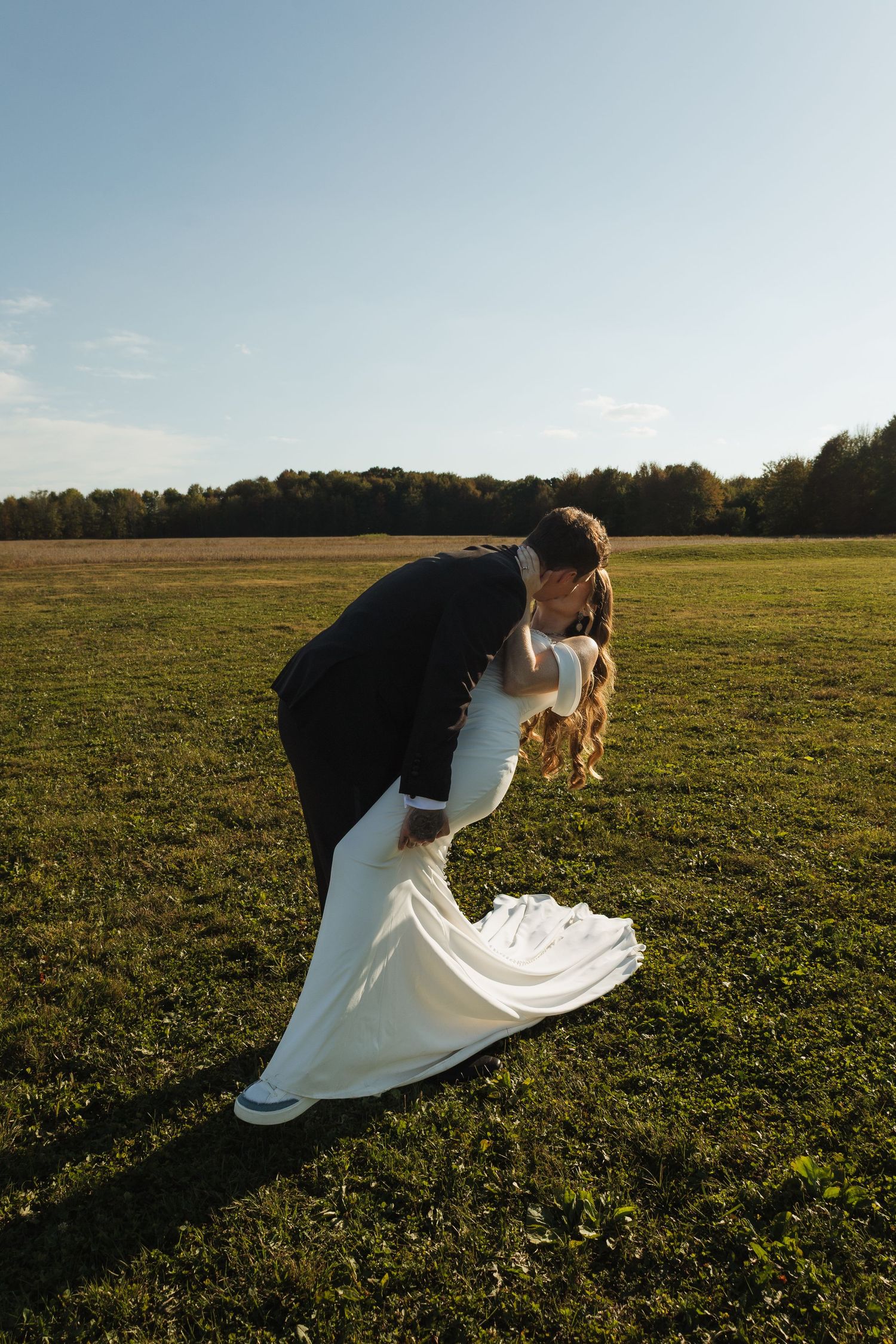 Wedding couple posing playfully in a sunlit meadow during their photo session.