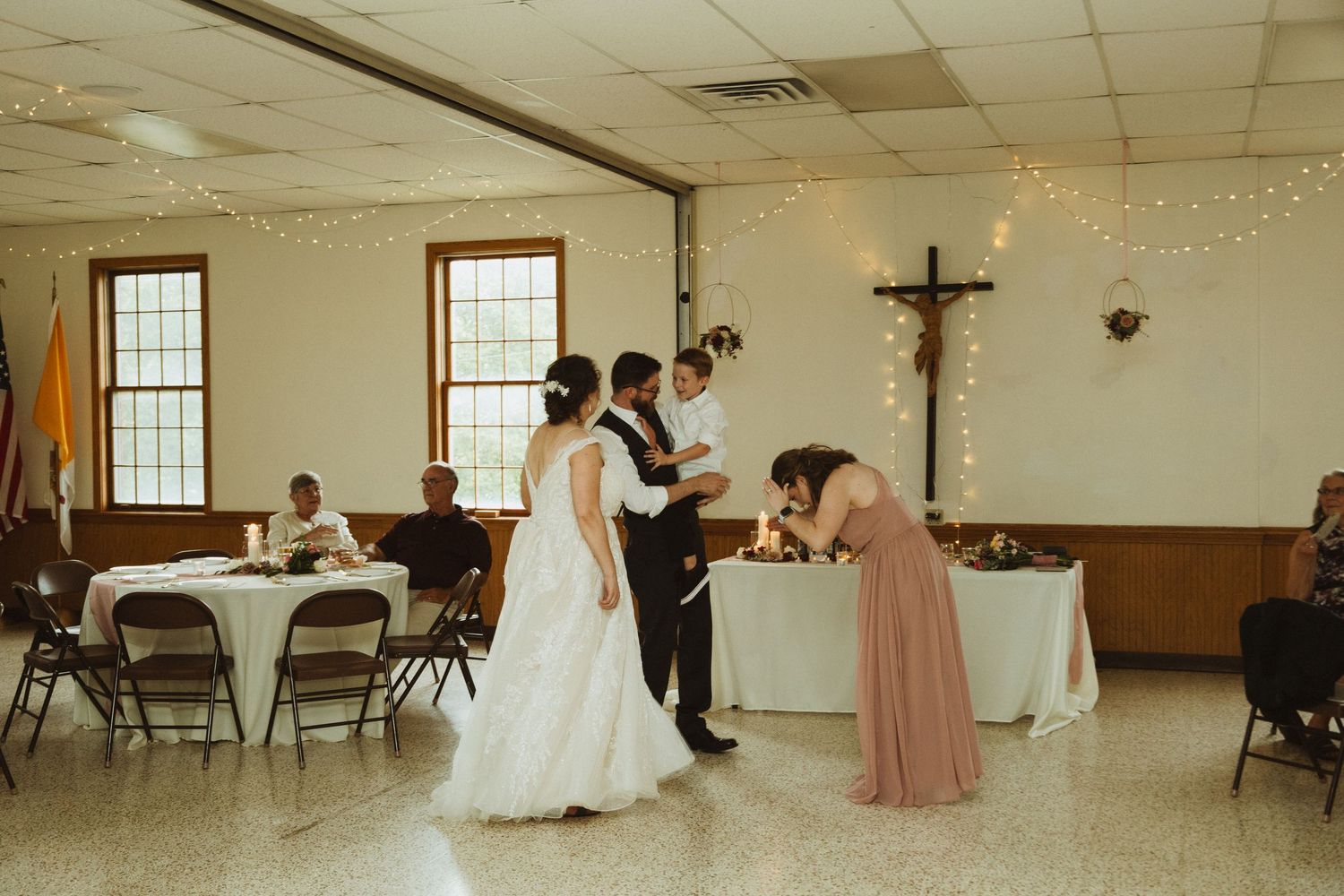 Church reception venue with wooden crucifix and windows decorated for wedding celebration.