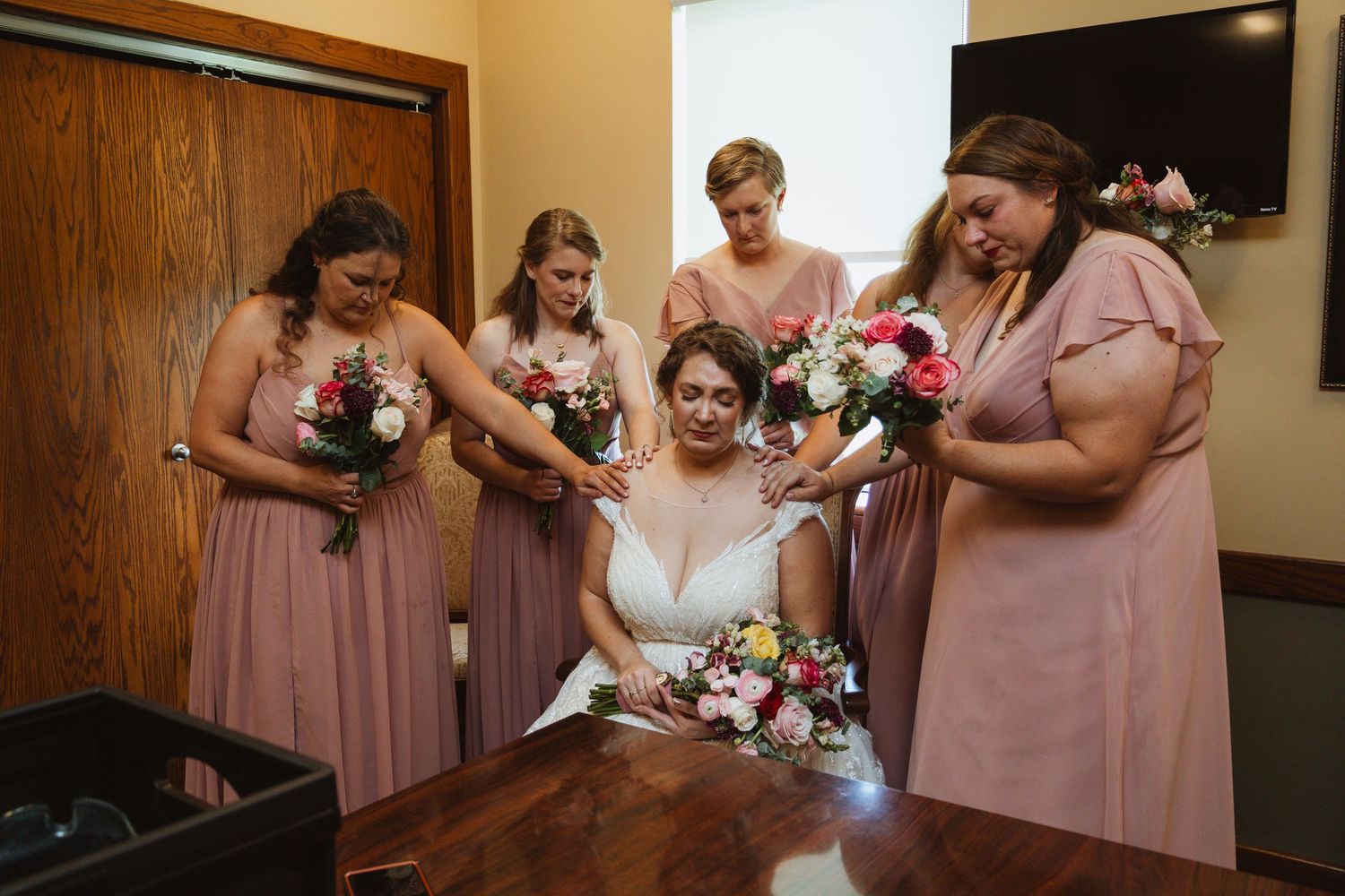 Wedding party in dusty rose dresses sharing candid moments during preparation.
