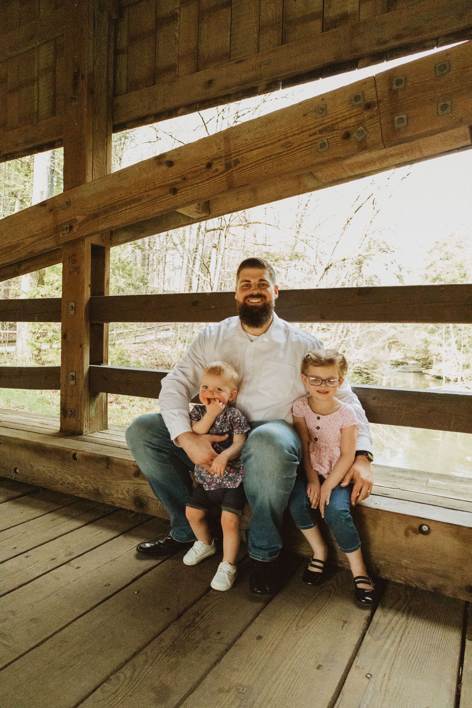 A heartwarming moment shared on a rustic wooden covered bridge overlooking water.