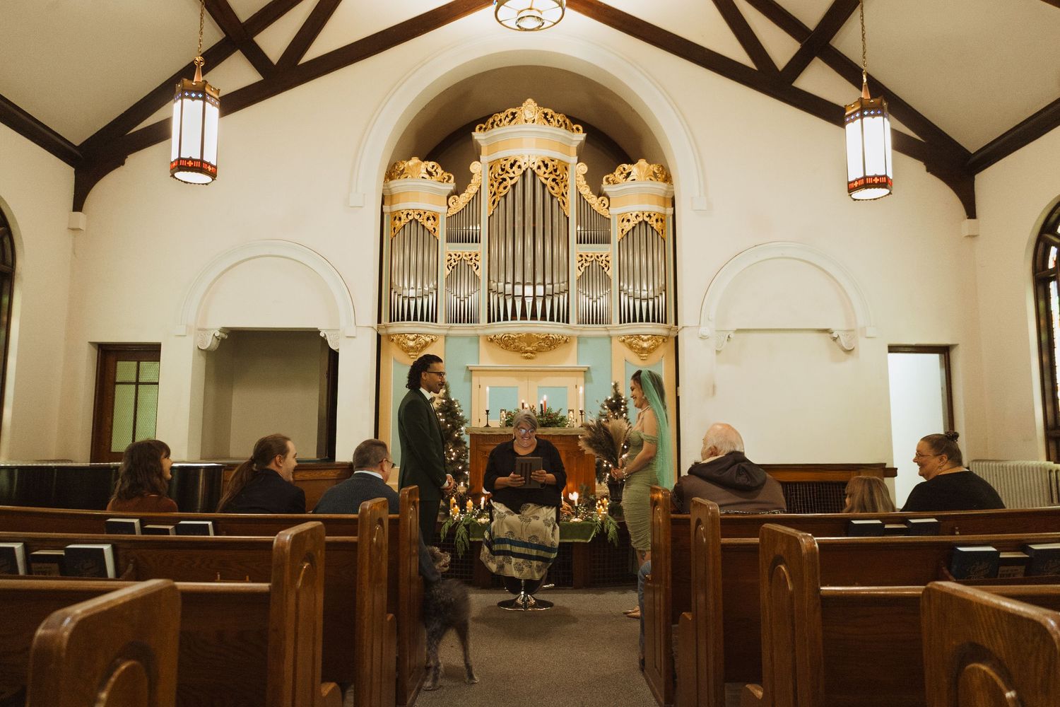Intimate wedding ceremony inside a historic church with pipe organ and wooden pews.