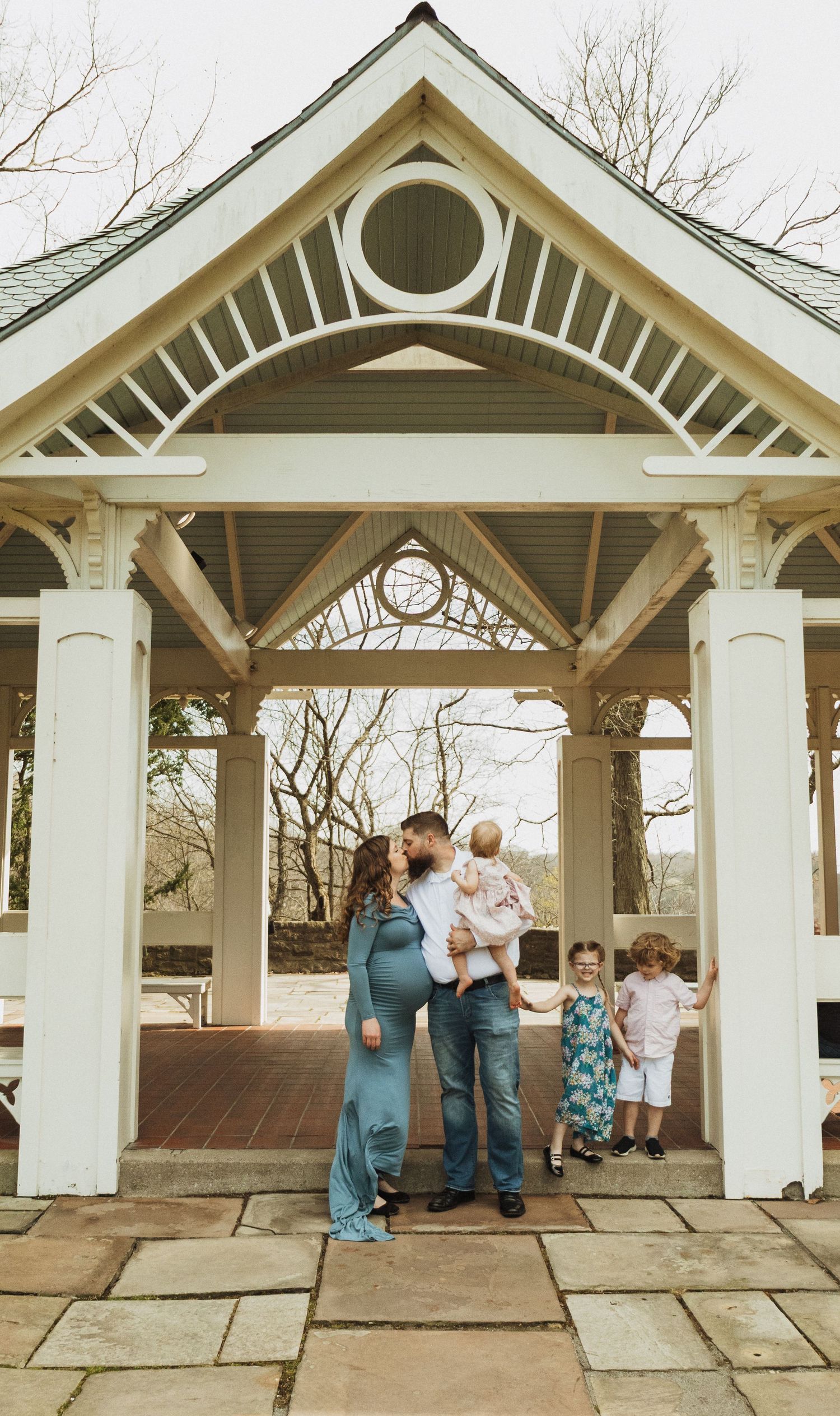 Family gathering under an elegant white gazebo with architectural details on a stone patio.