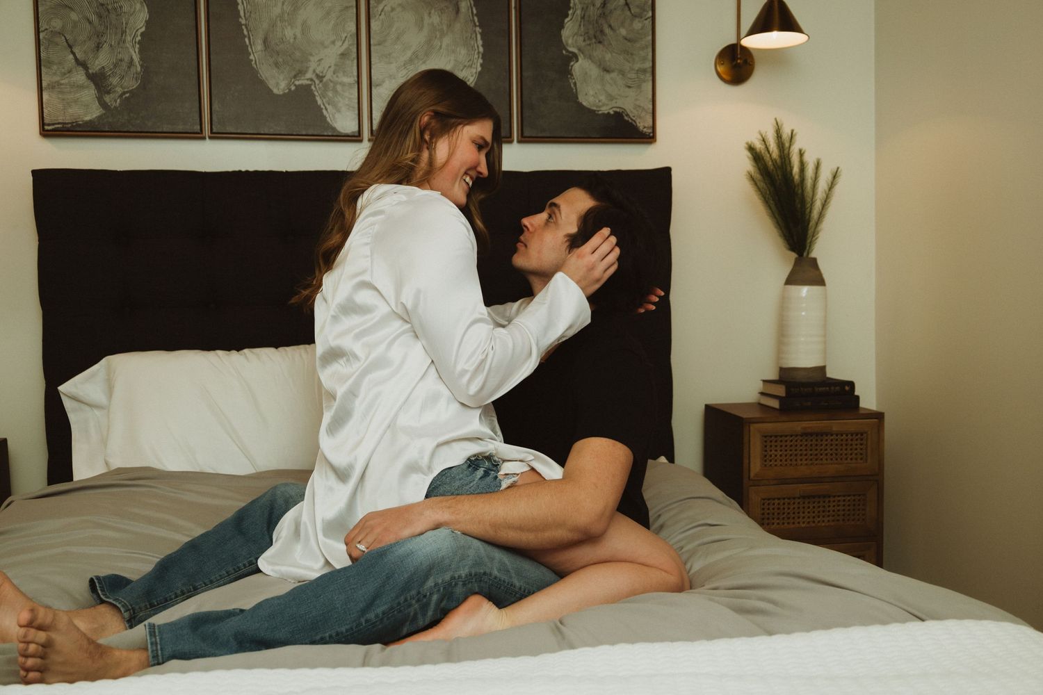 Intimate moment captured in modern bedroom with abstract wall art and warm lighting.