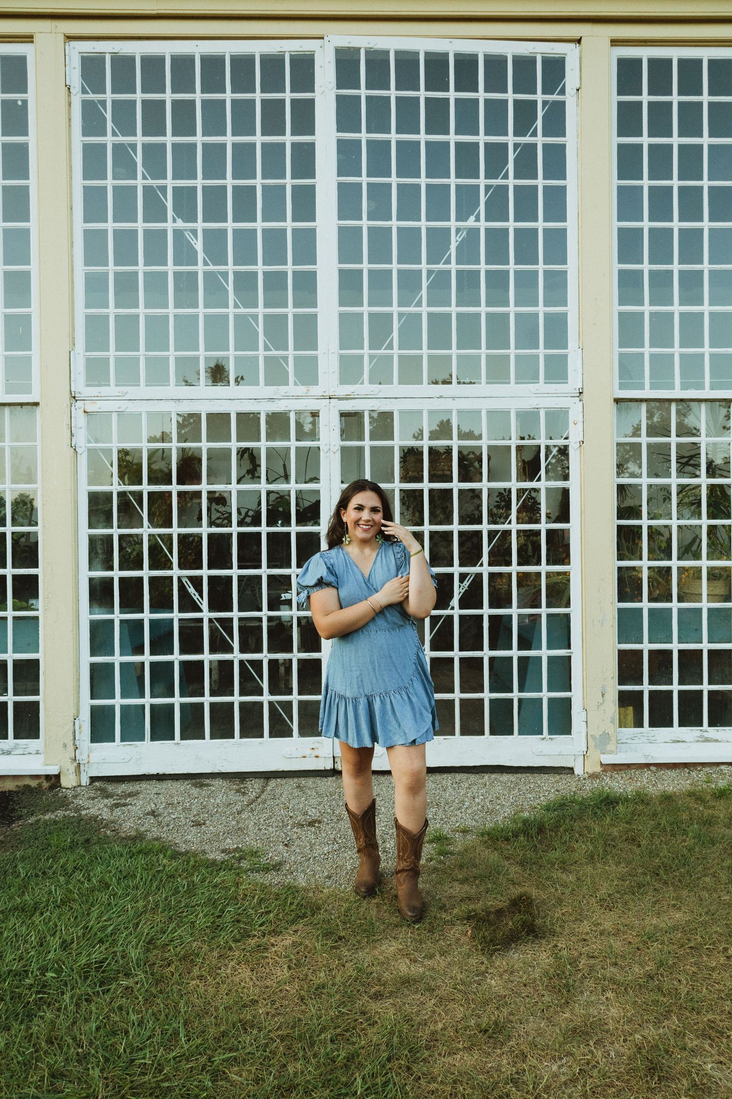 A sequence of images showing a person in blue dress and brown boots sliding down a grassy hill beside windows.
