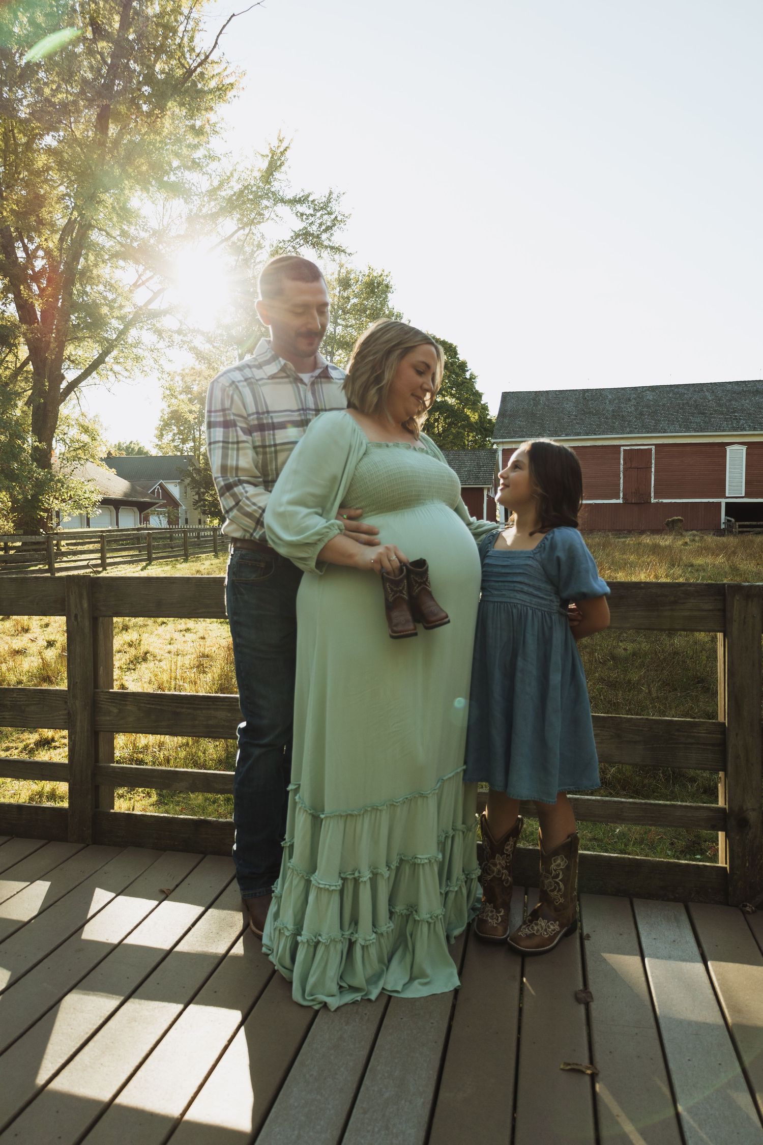 Family shares candid moments and laughter while standing on a wooden deck at sunset.