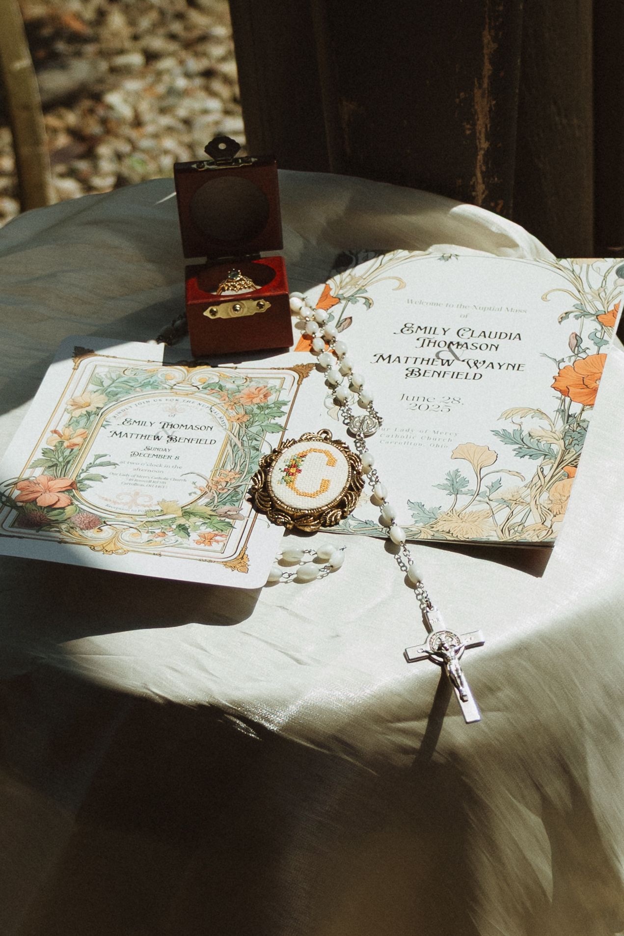 Elegant floral wedding invitations displayed on white fabric in natural lighting.