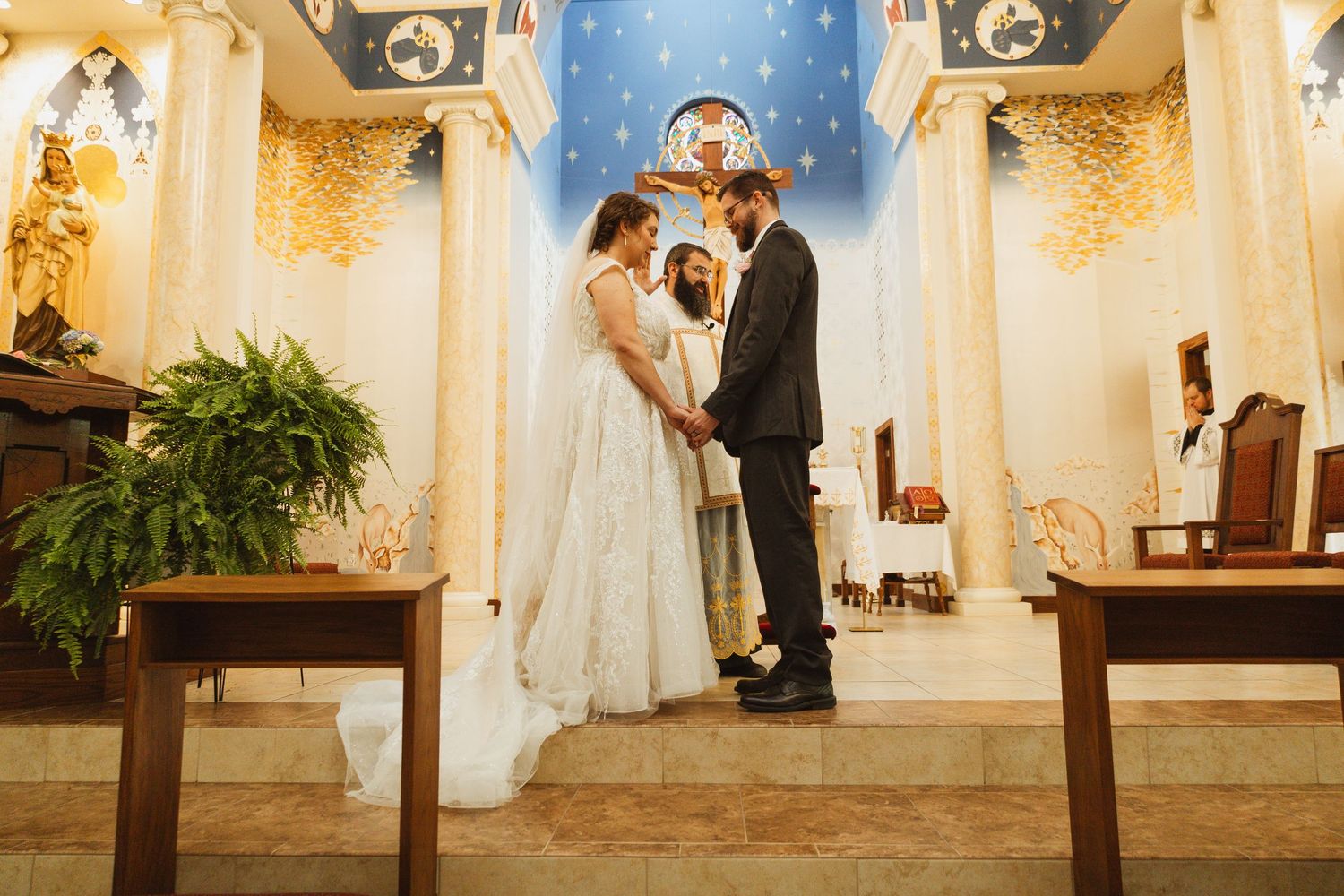 A wedding ceremony in progress inside an ornate church with blue and gold accents.